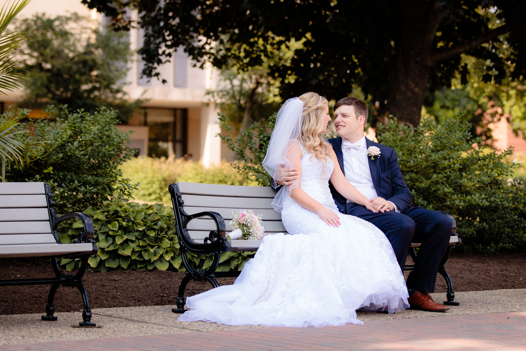 Newlyweds sit on a bench on Academic Walk at Duquesne University