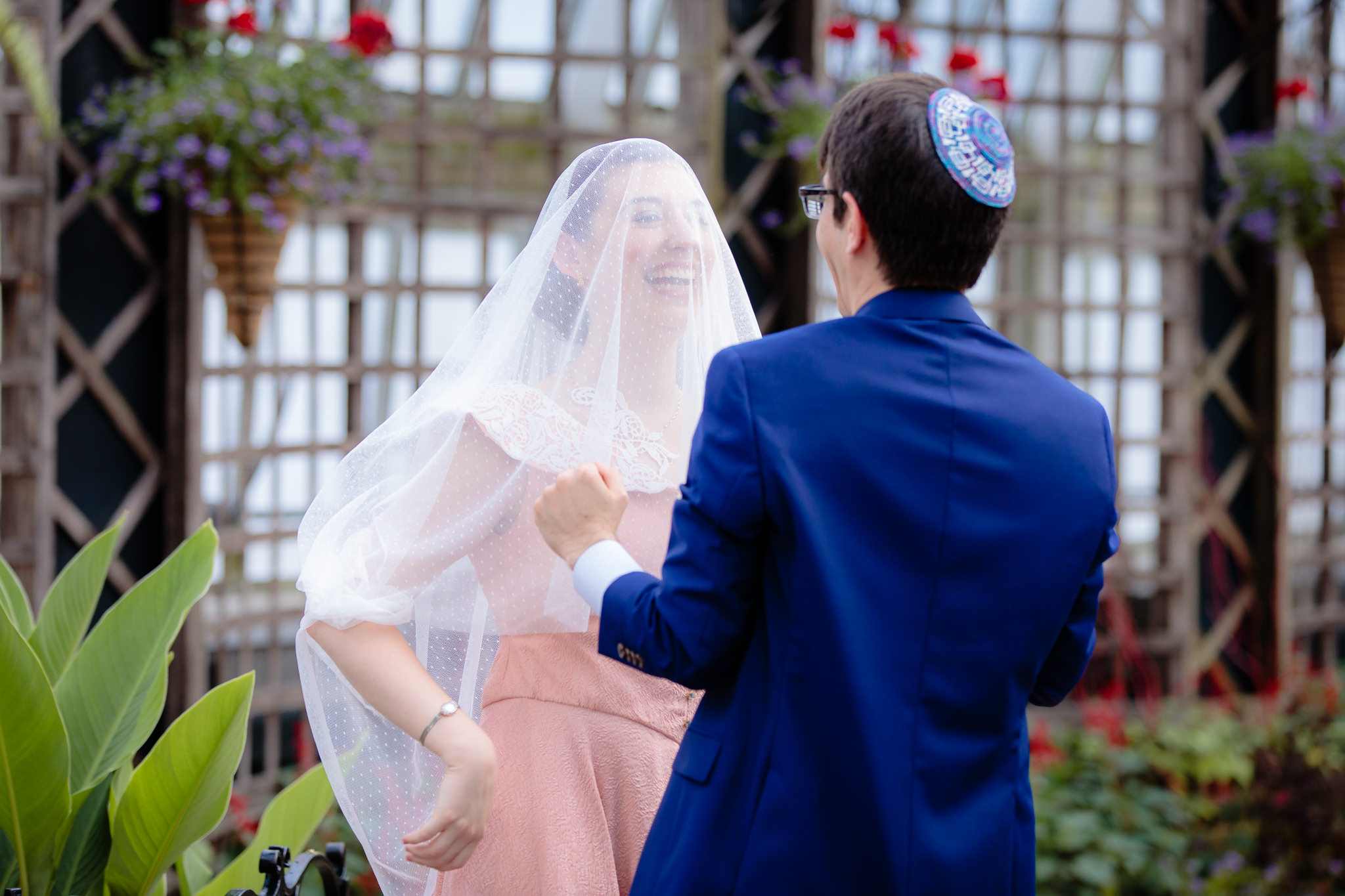 Groom lowers the bride's veil over her face during their Bedeken ceremony at Phipps Conservatory