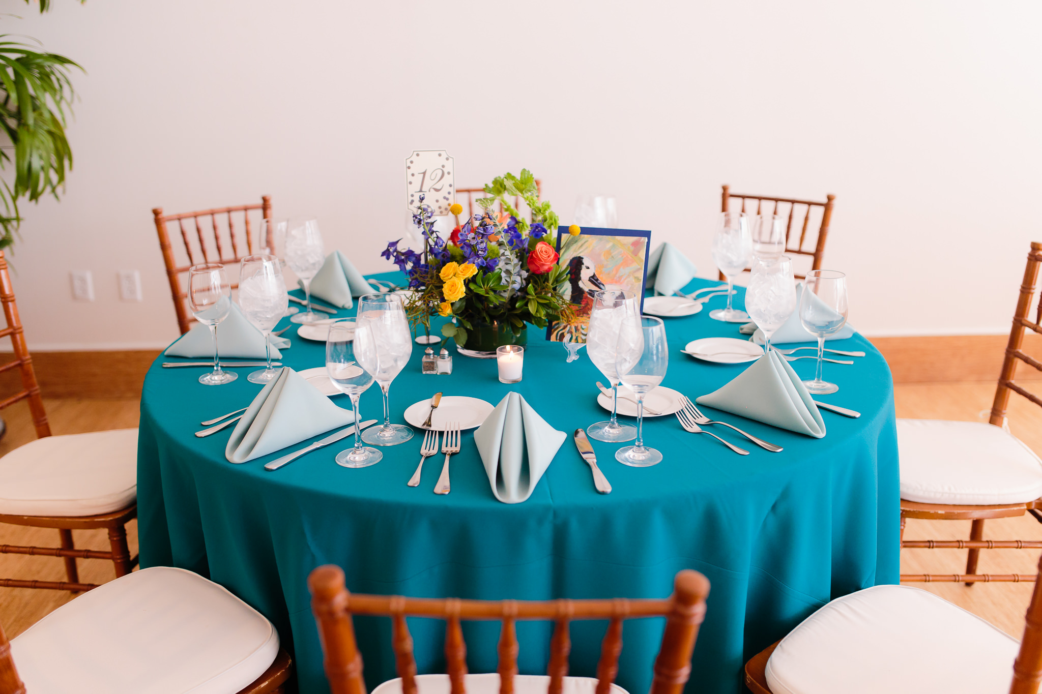 Teal tablecloths and colorful flowers by Hepatica decorate each table at a Phipps Conservatory wedding