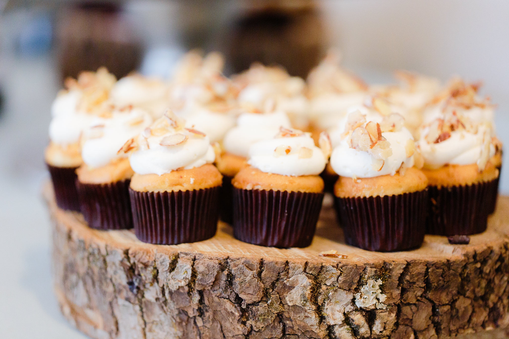 Small almond cupcakes by Bella Christie & Lil Z's Sweet Boutique sit atop a rustic cake tray
