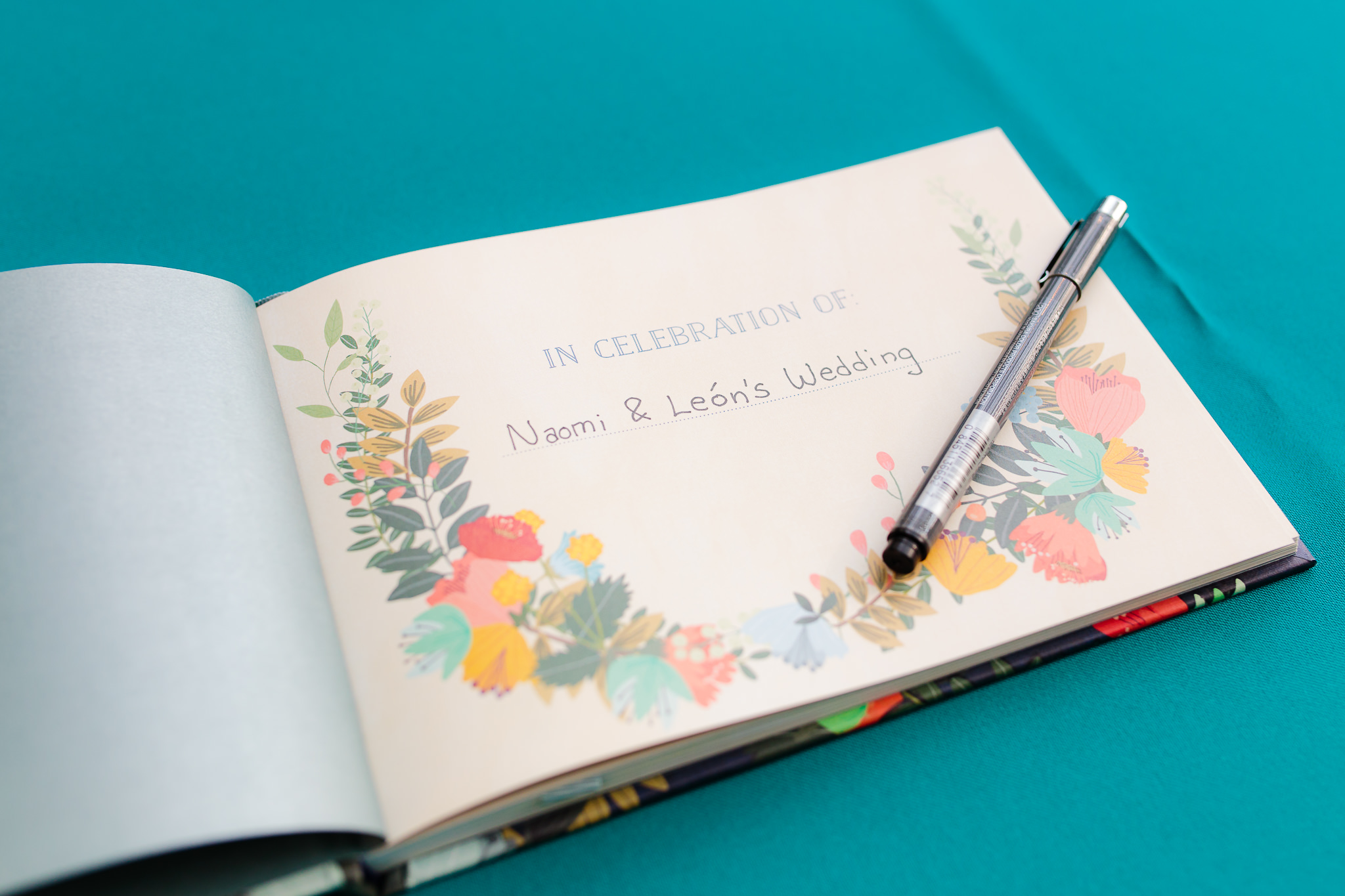 Guestbook with floral designs sits on a teal table cloth waiting to be signed at Phipps Conservatory