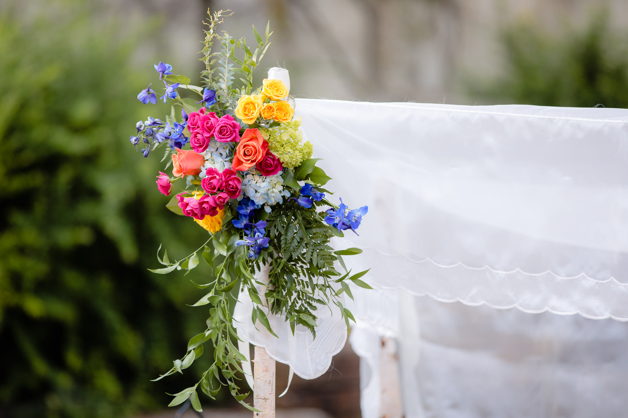 Bright colorful flowers adorn the chuppah at a Jewish wedding ceremony at Phipps Conservatory