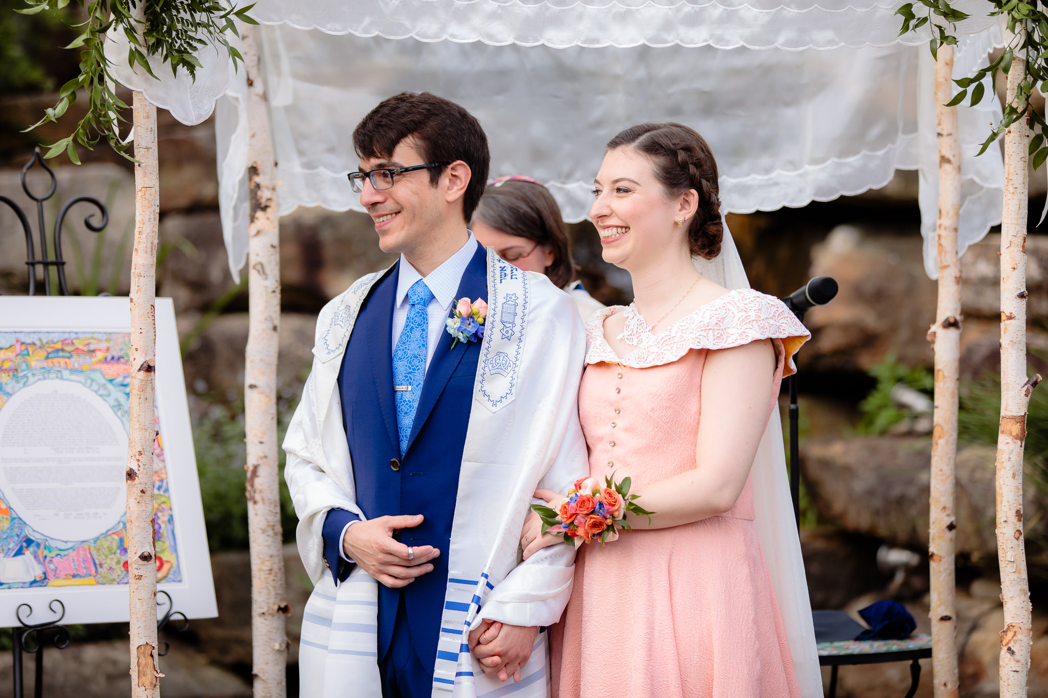 Bride and groom smile under the chuppah at a Jewish wedding at Phipps Conservatory
