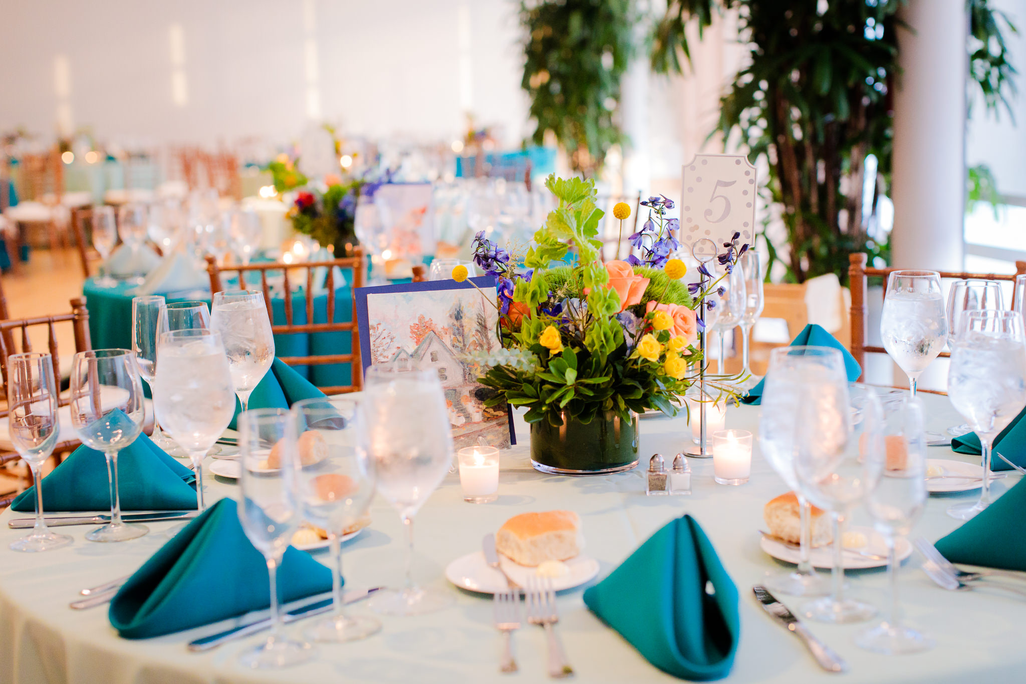 Tables set with turquoise linens and floral centerpieces at Phipps Conservatory