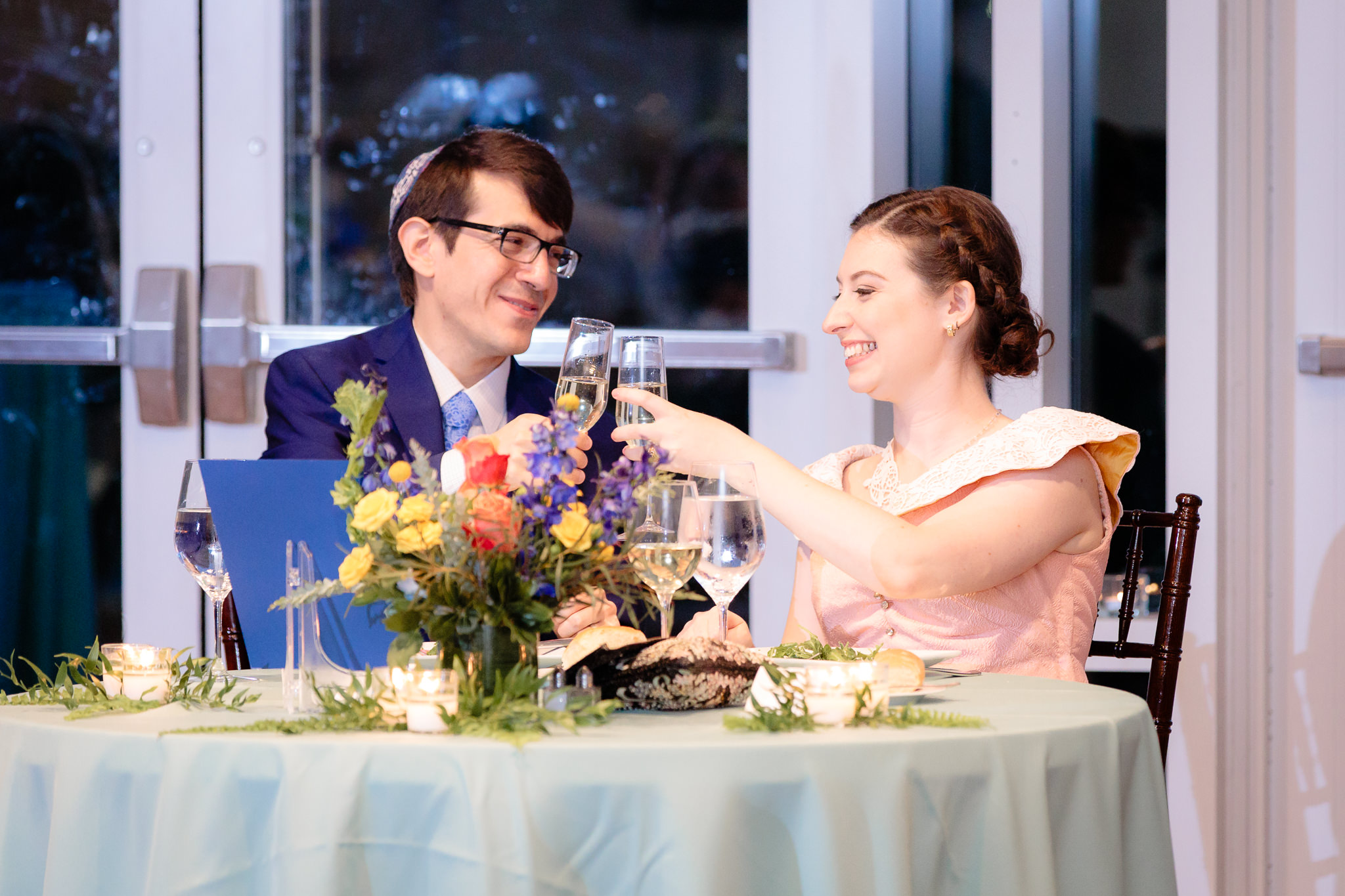 Bride & groom clink glasses during toasts at their Phipps Conservatory wedding reception