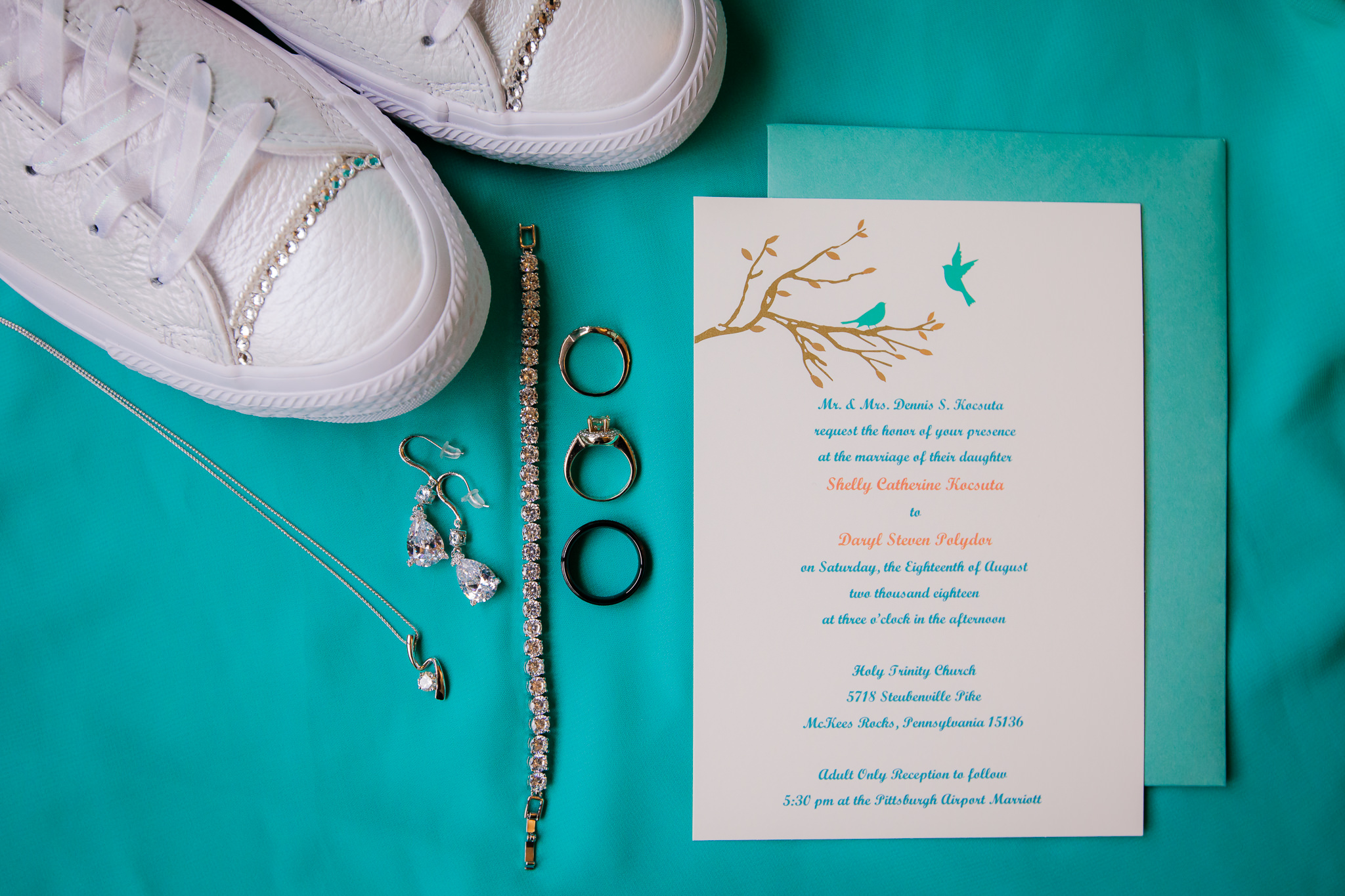 Bride's details laid out on a turquoise bridesmaid dress
