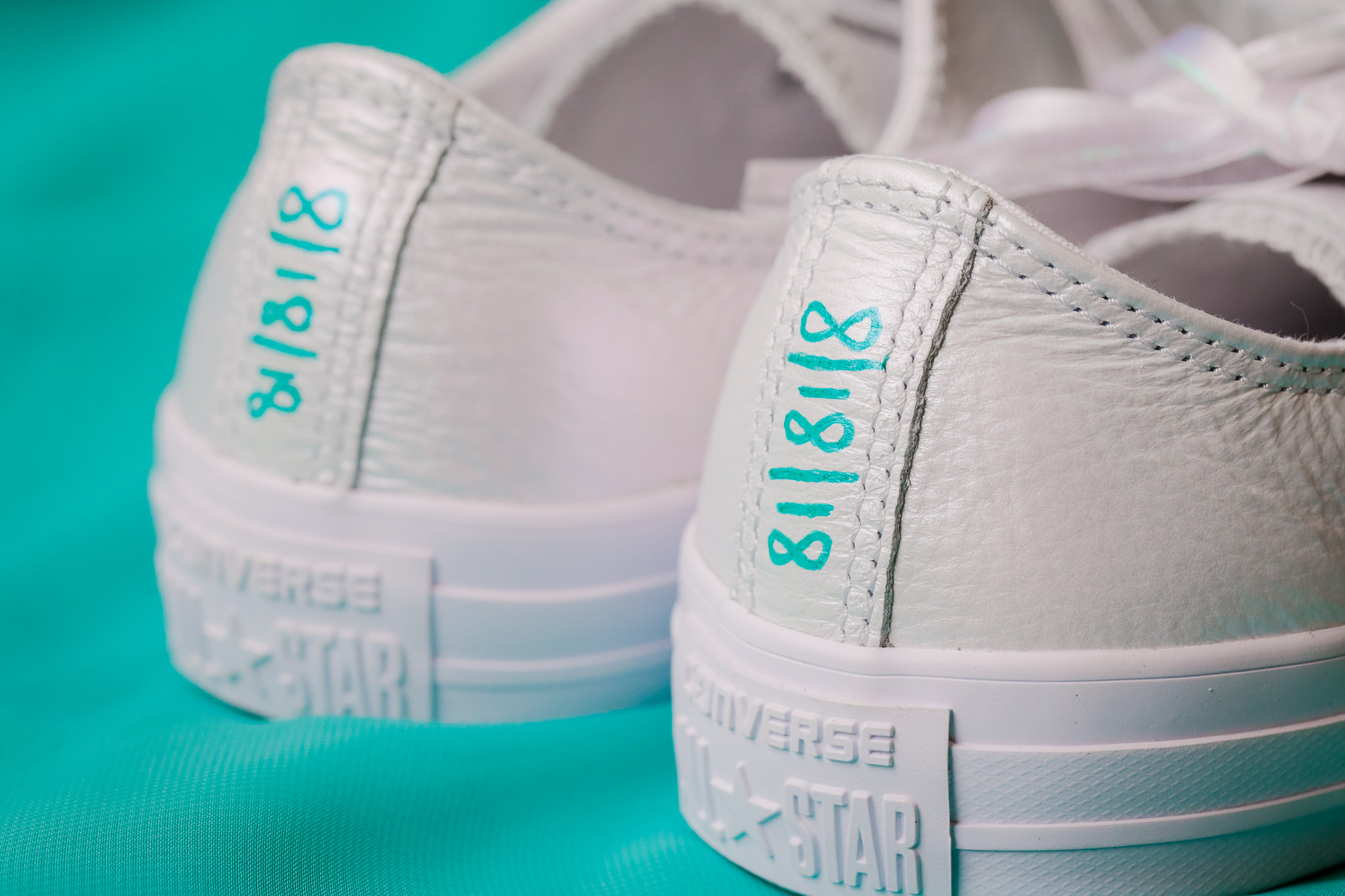Wedding date written in turquoise Sharpie on the back of the bride's white Converse All Stars