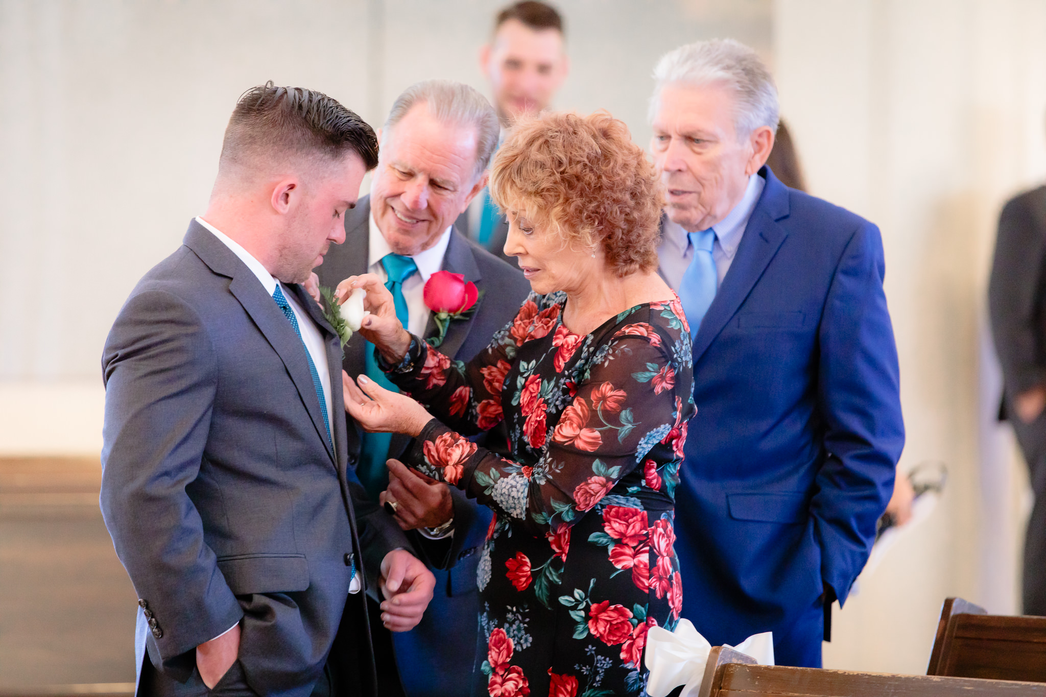 Groom's grandmother pins on his boutonniere at Holy Trinity Catholic Church
