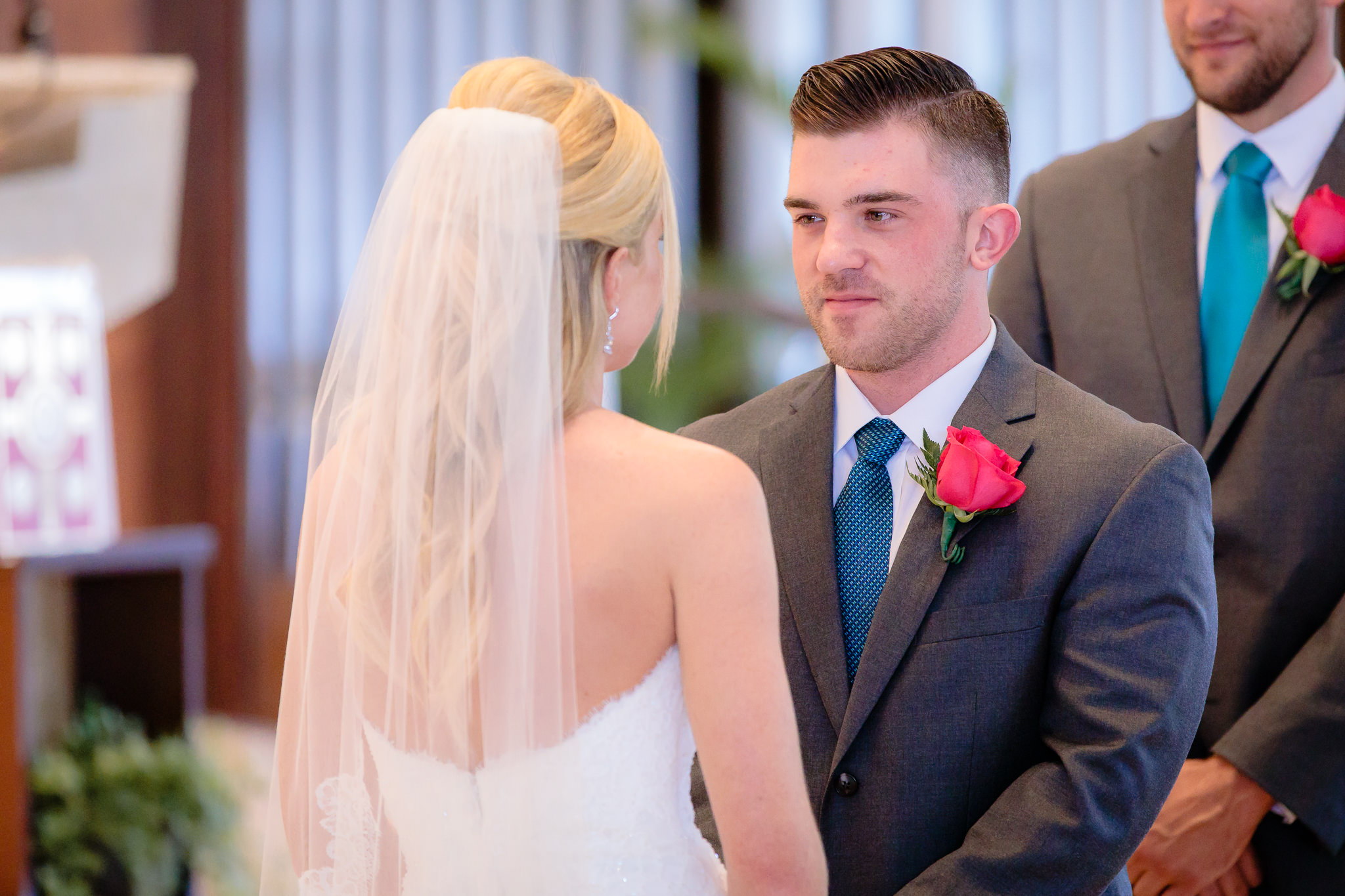Groom smiles at the bride during vows at Holy Trinity Catholic Church
