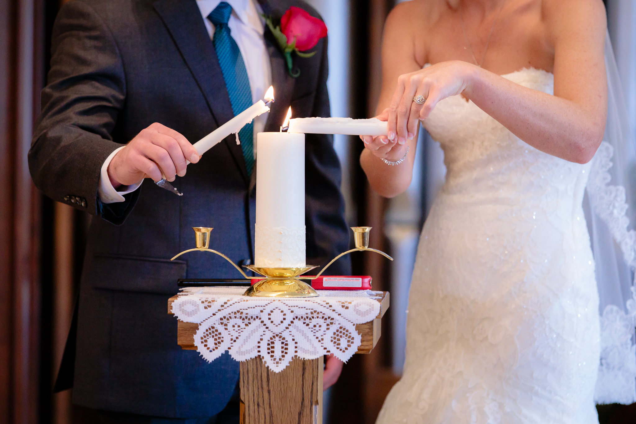 Closeup of bride & groom's hands lighting the unity candle at Holy Trinity Catholic Church