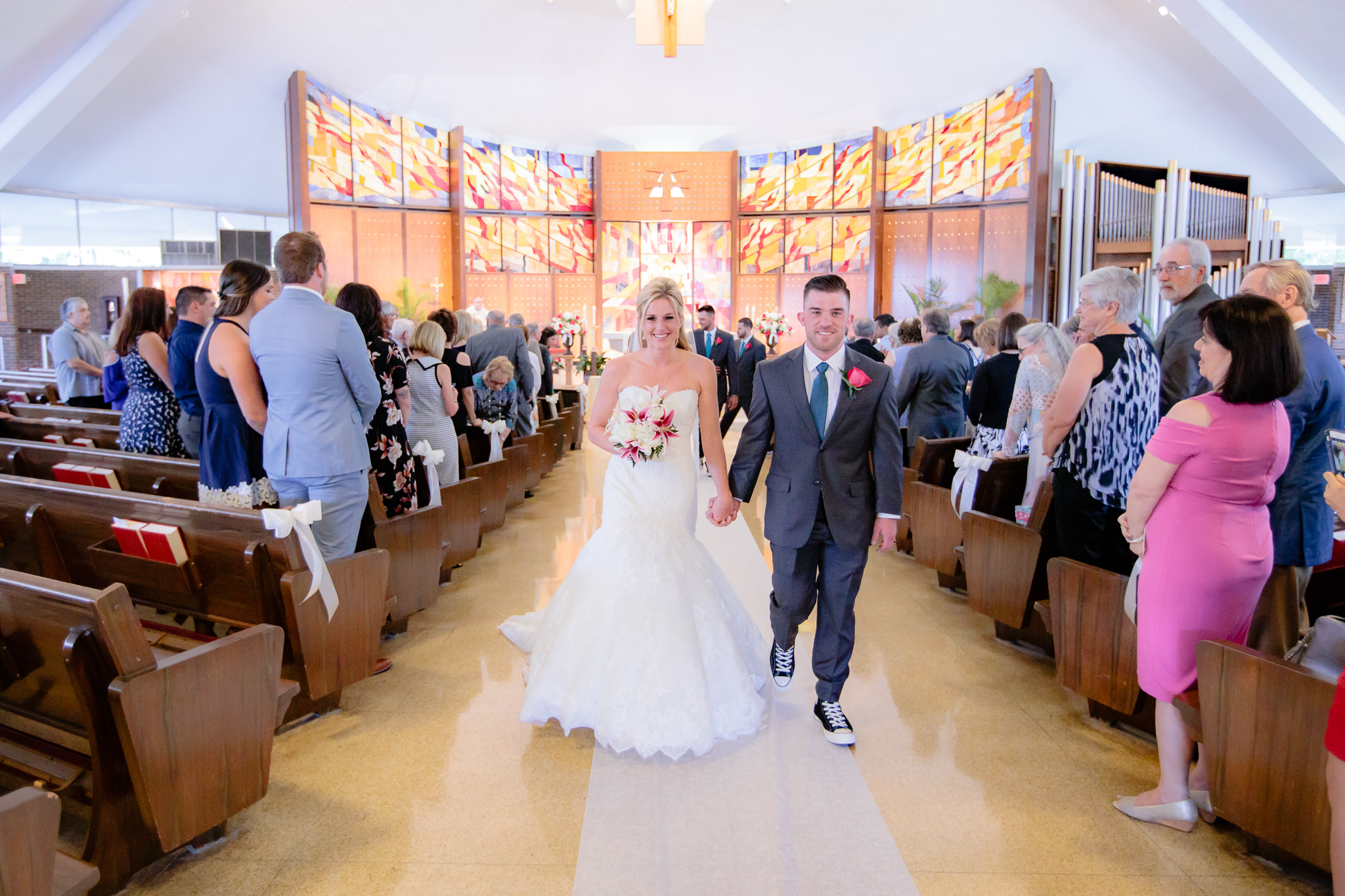 Newlyweds exit their Holy Trinity Catholic Church wedding ceremony holding hands