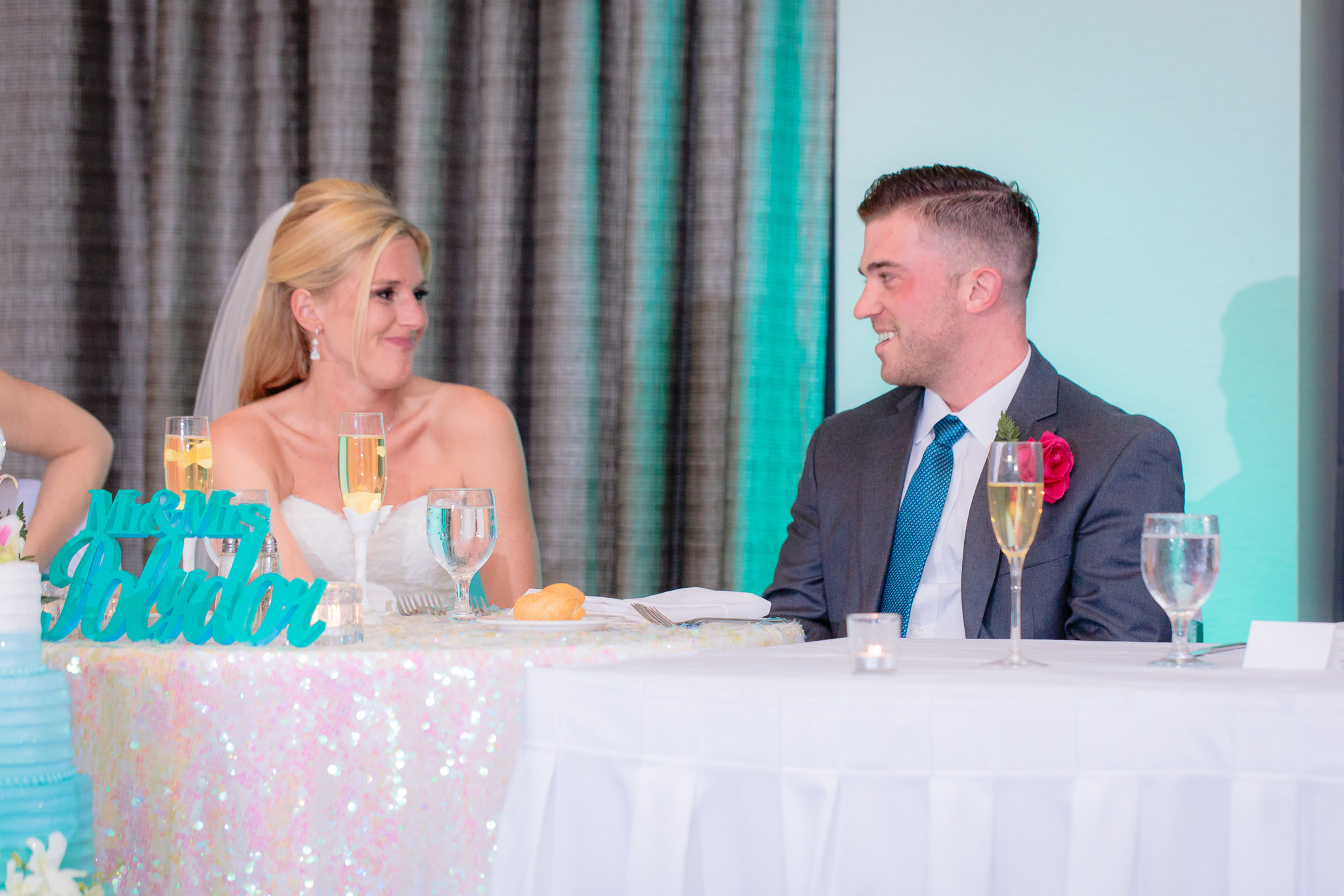 Newlyweds smile at each other during speeches at the Pittsburgh Airport Marriott
