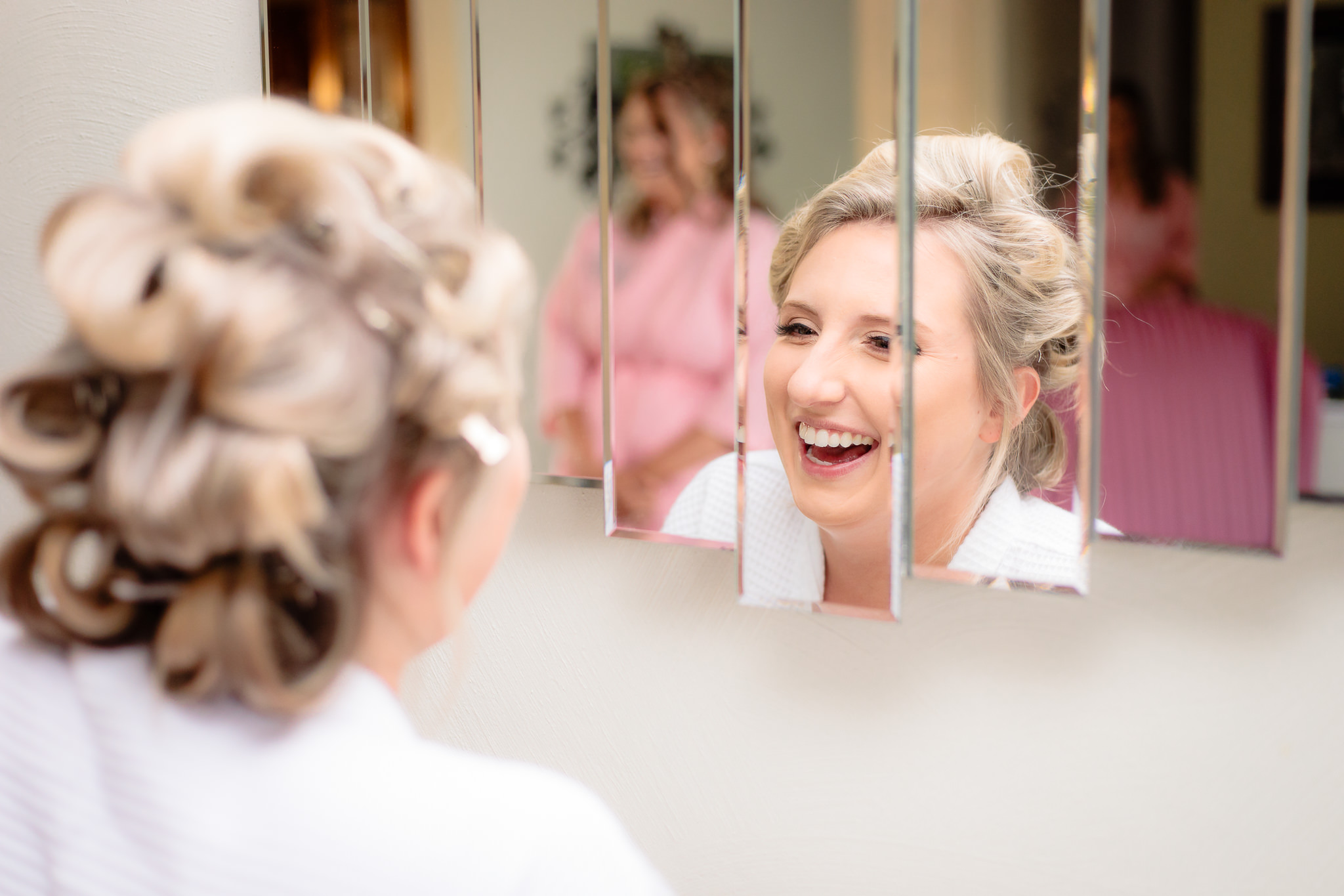Bride laughs in the mirror before her Greystone Fields wedding