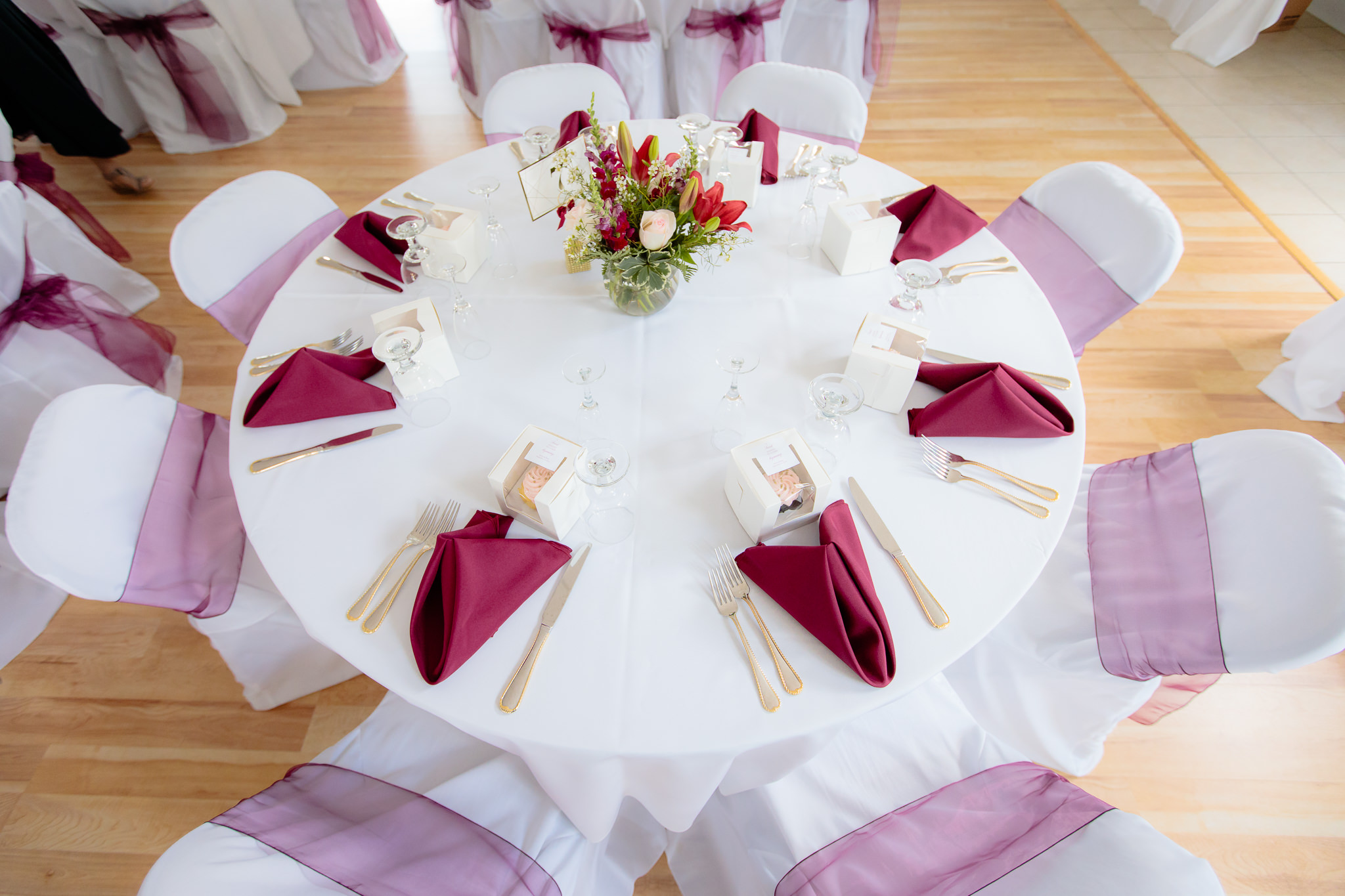 Tablescape of gold flatware and burgundy linens at a Greystone Fields wedding reception