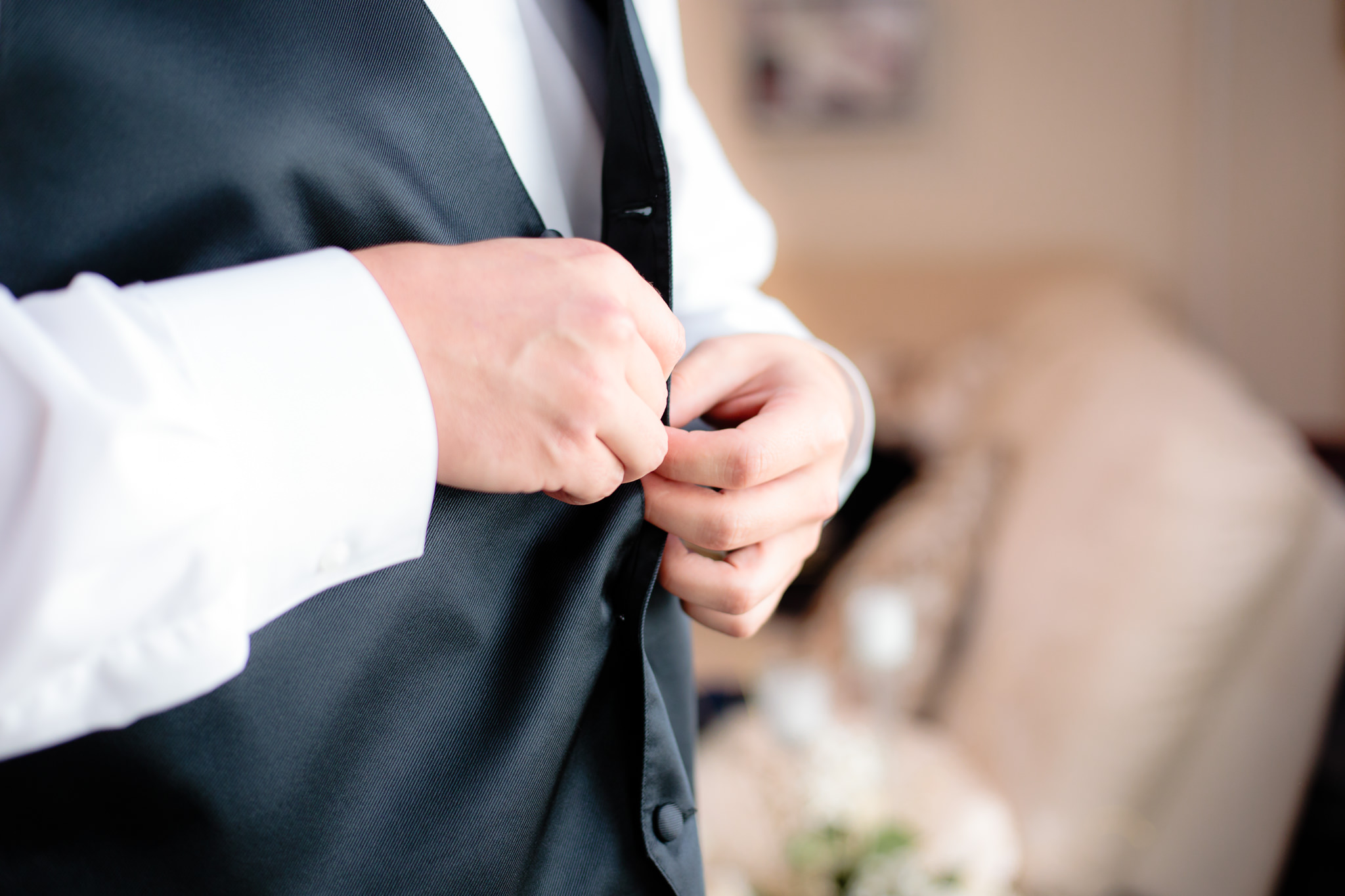 Groom buttons his vest before his wedding at Greystone Fields