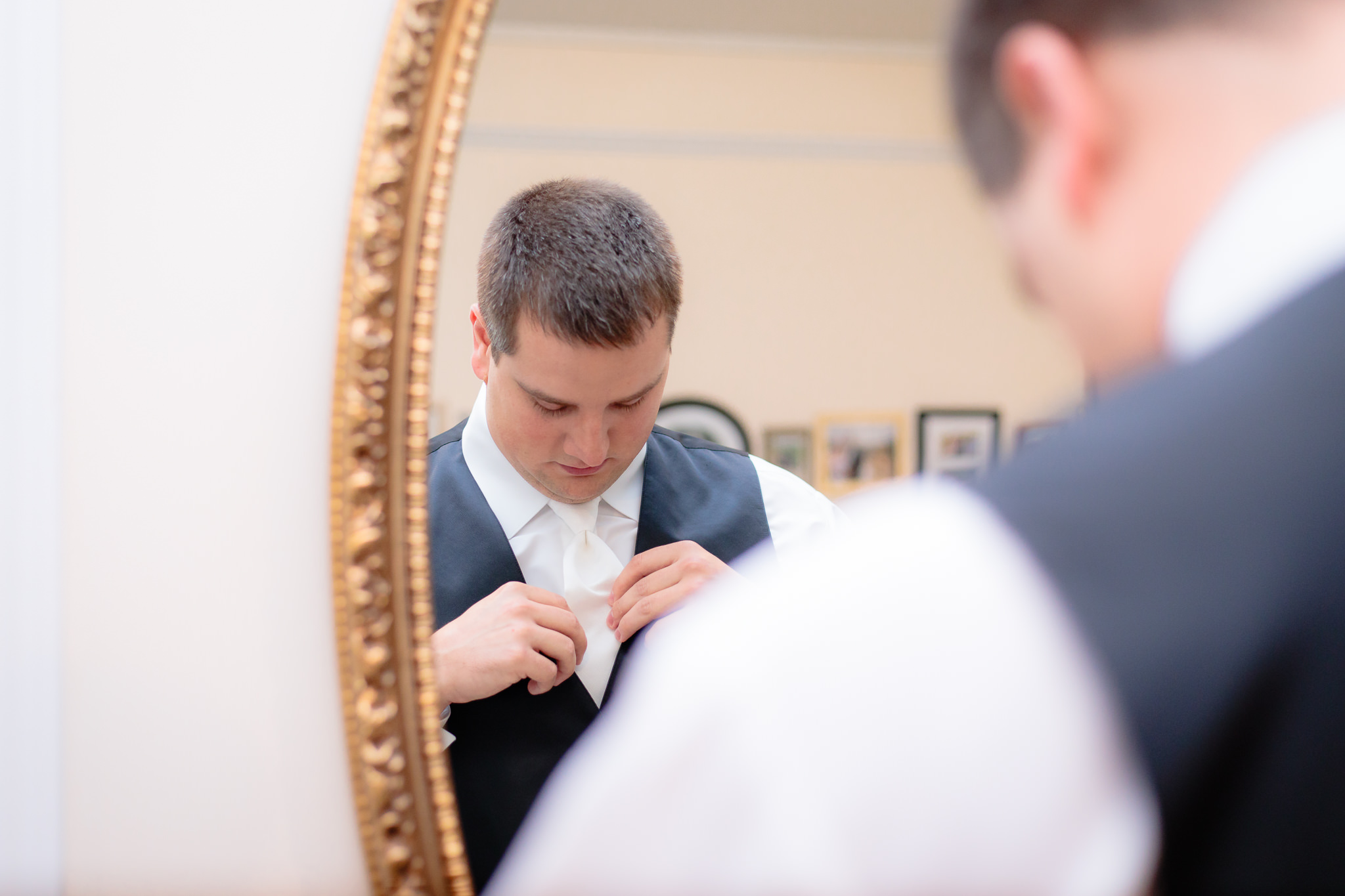 Groom fixes his tie in the mirror at Greystone Fields
