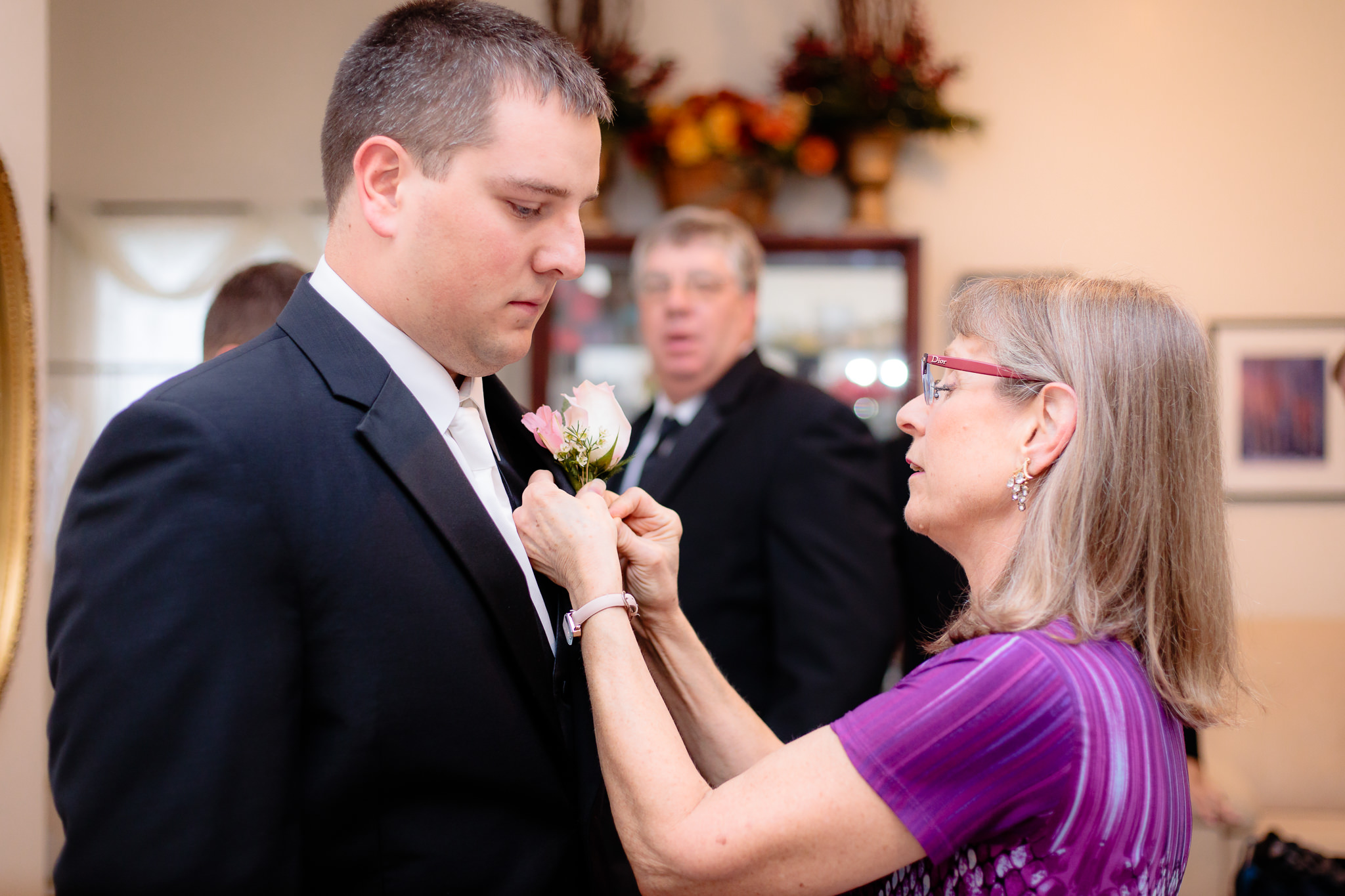 Susan Talbot pins the groom's boutonniere at a Greystone Fields wedding
