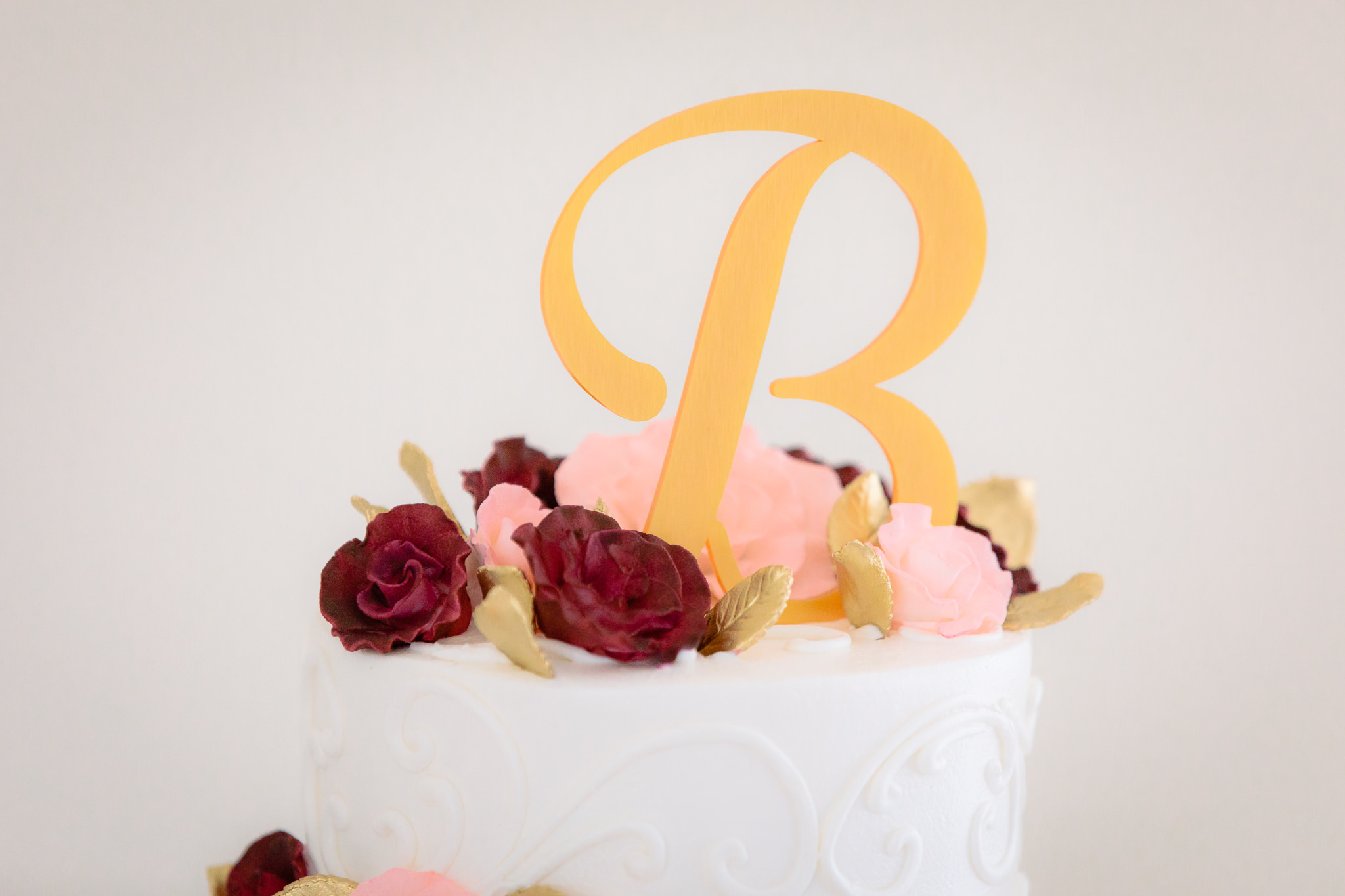 Monogram and floral cake topper on a wedding cake by Oakmont Bakery at Greystone Fields