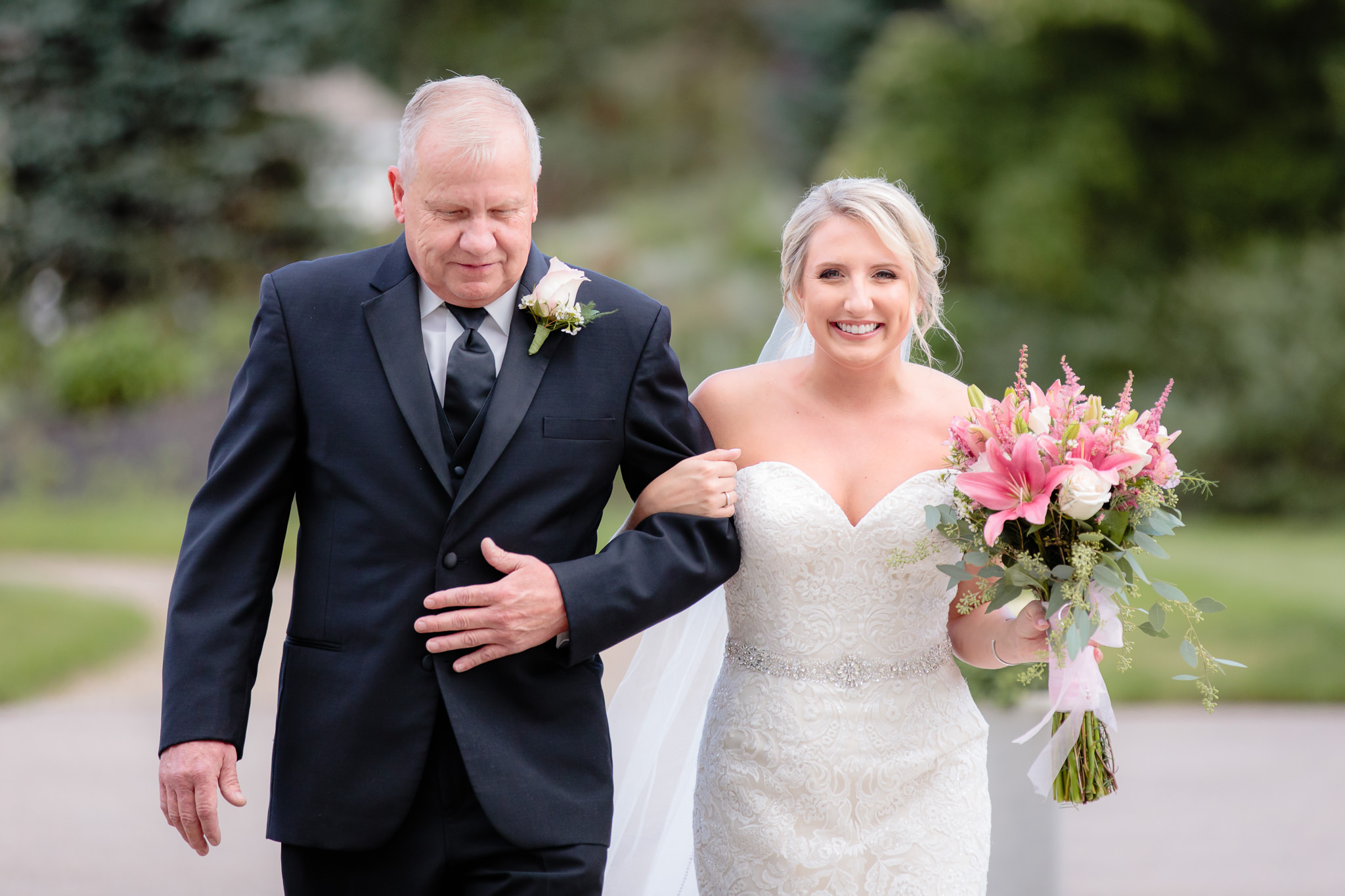 Bride smiles as her father walks her down the aisle at Greystone Fields