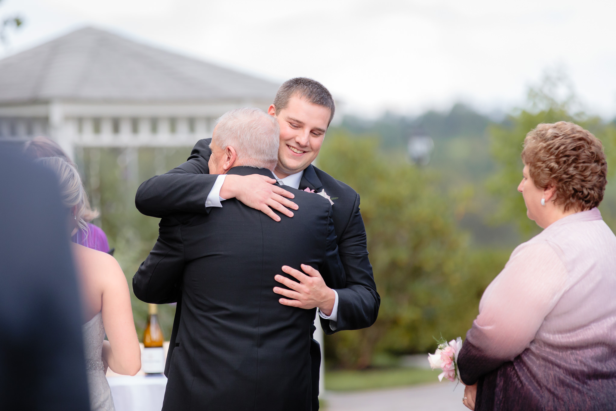 Groom hugs the bride's father at a Greystone Fields wedding ceremony