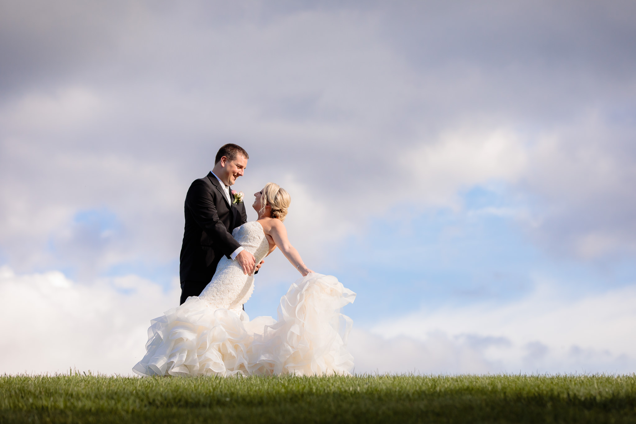 Groom dips his bride on top of a hill at Greystone Fields