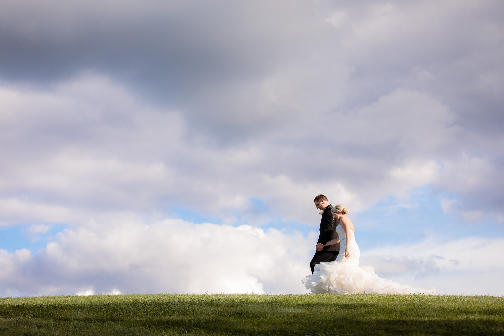 Bride & groom walk together on a hilltop at Greystone Fields
