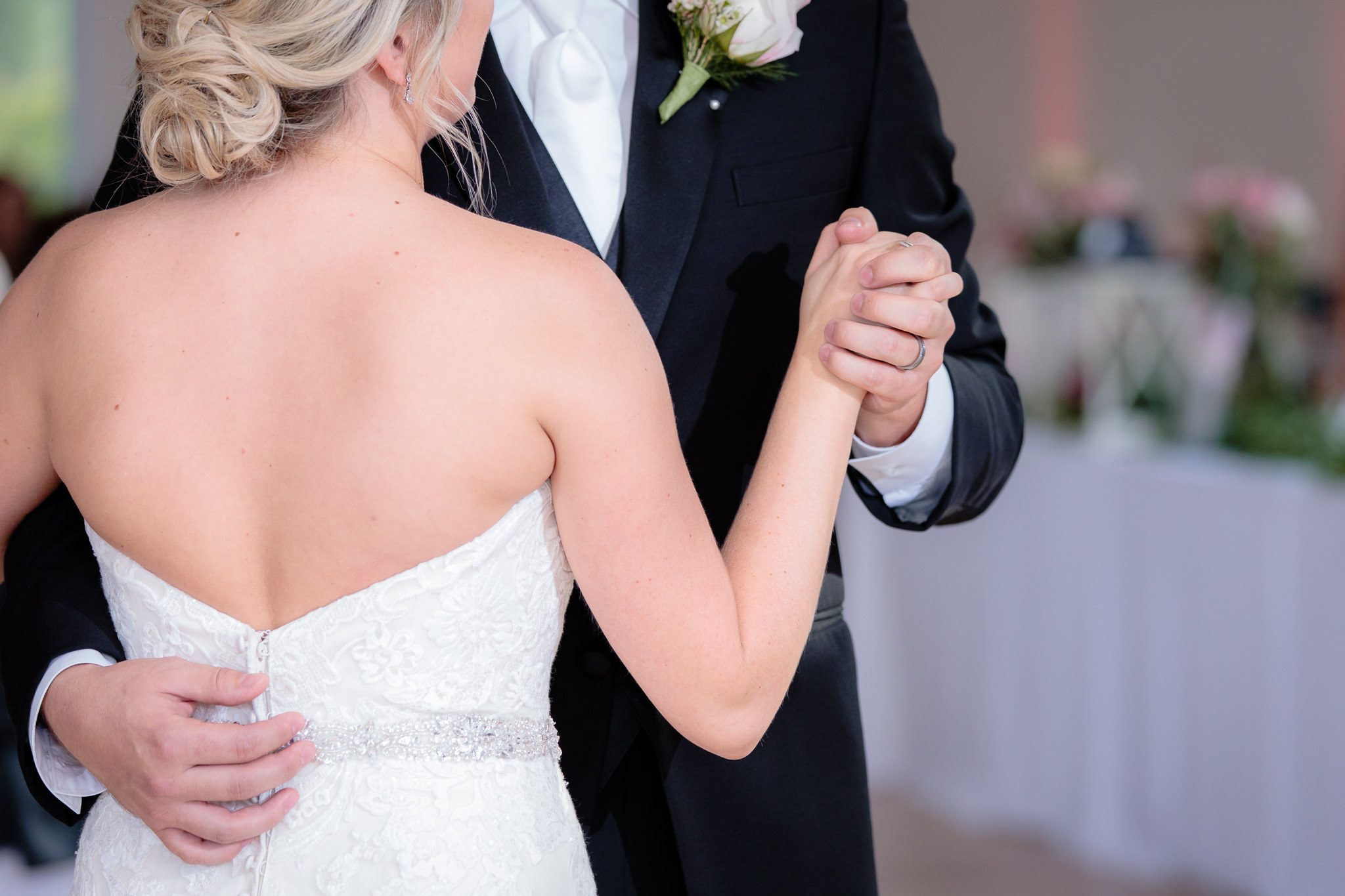 Closeup of groom holding bride's hand during first dance at Greystone Fields
