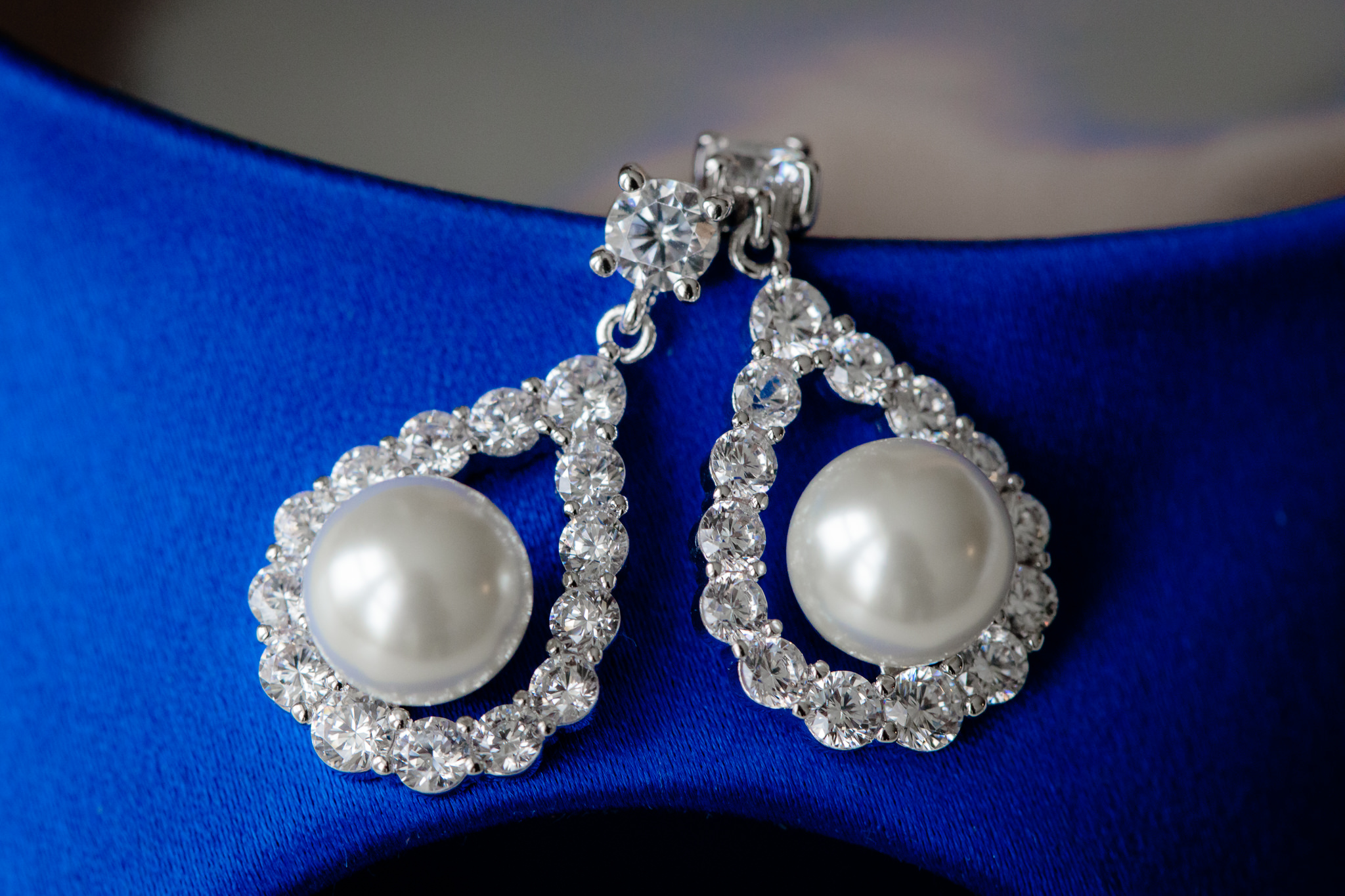 Bride's diamond & pearl teardrop earrings rest on her royal blue shoes