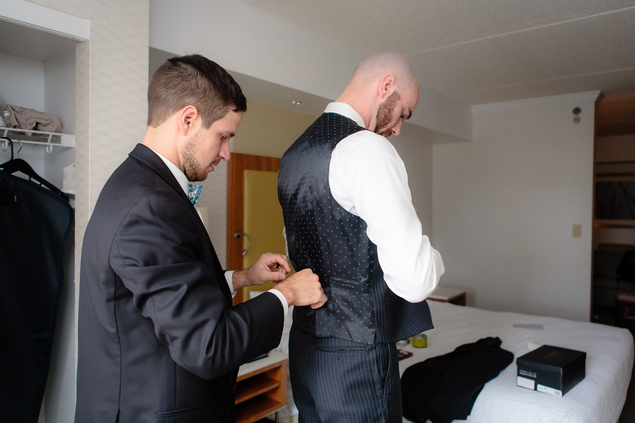 Groomsmen helps the groom get dressed before his National Aviary wedding