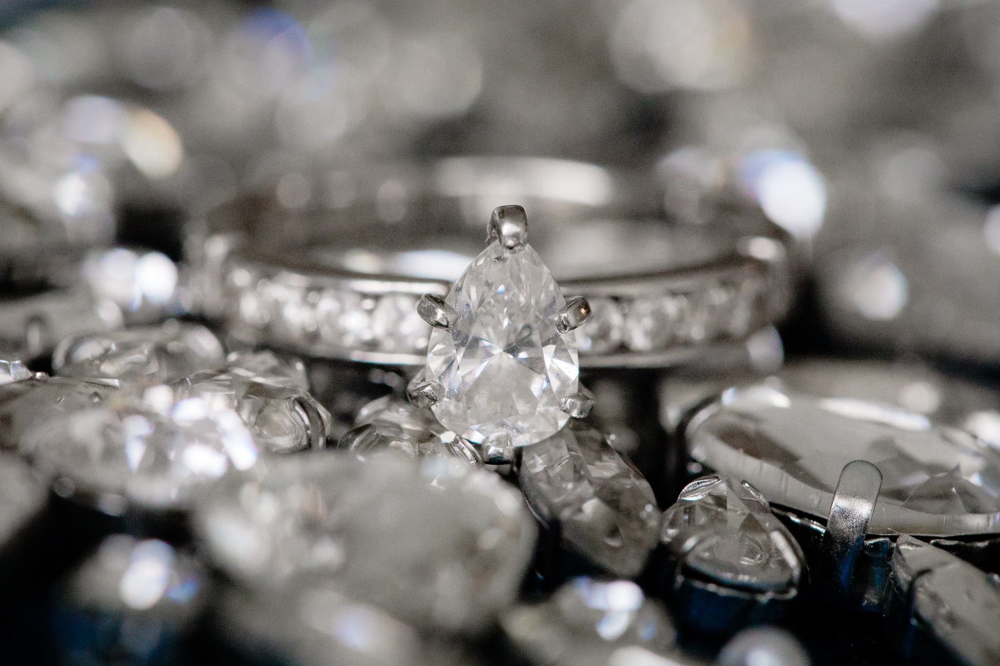 Bride's teardrop diamond engagement ring rests on a bed of rhinestones