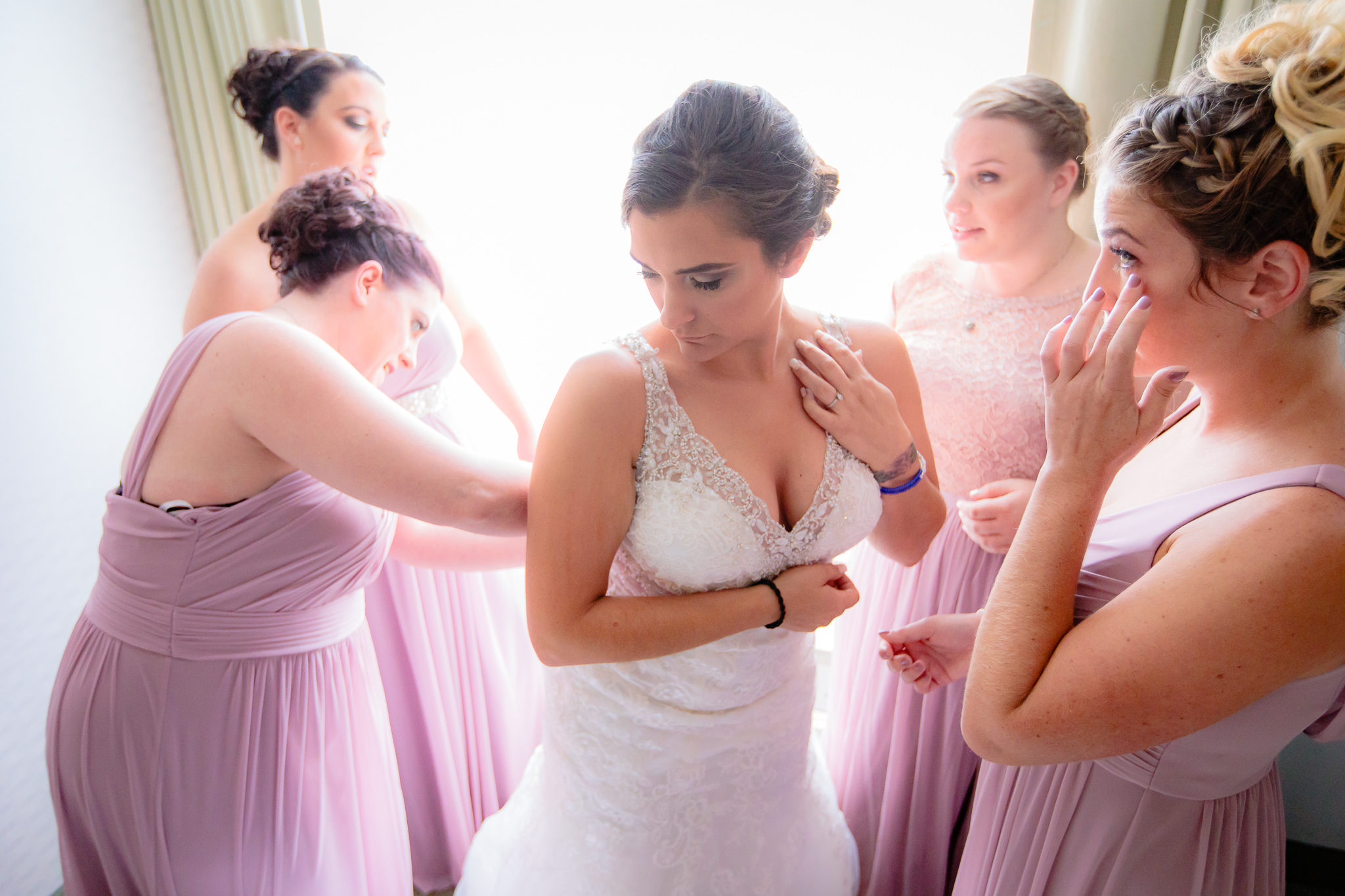 Bridesmaids help the bride into her dress before a National Aviary wedding