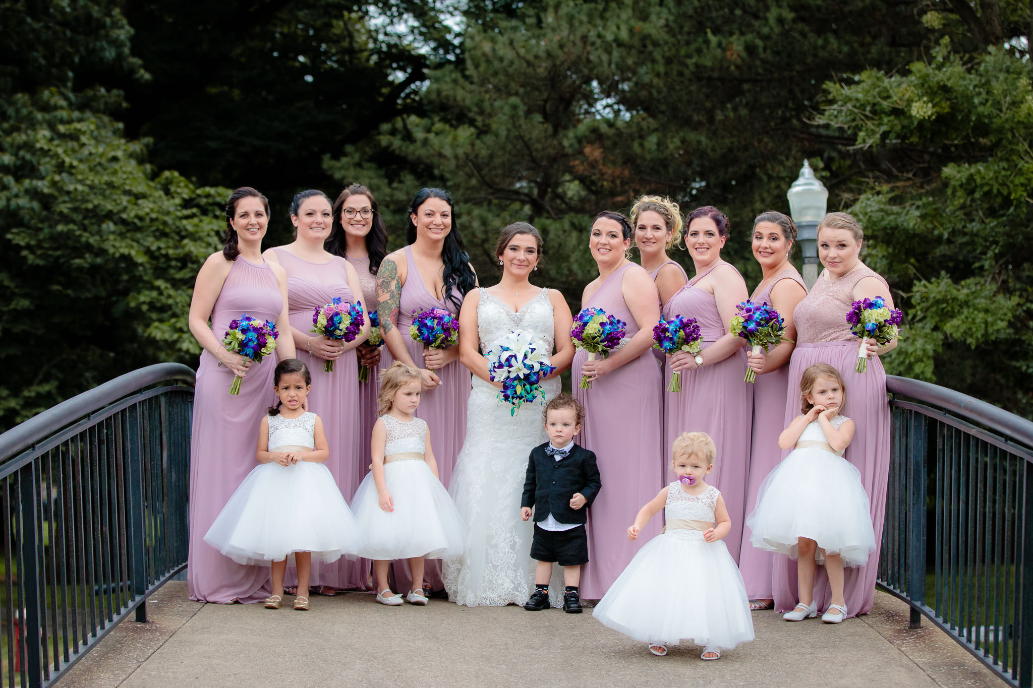 Bridesmaids, flower girls, & ring bearer pose with the bride on a bridge in Allegheny Commons Park