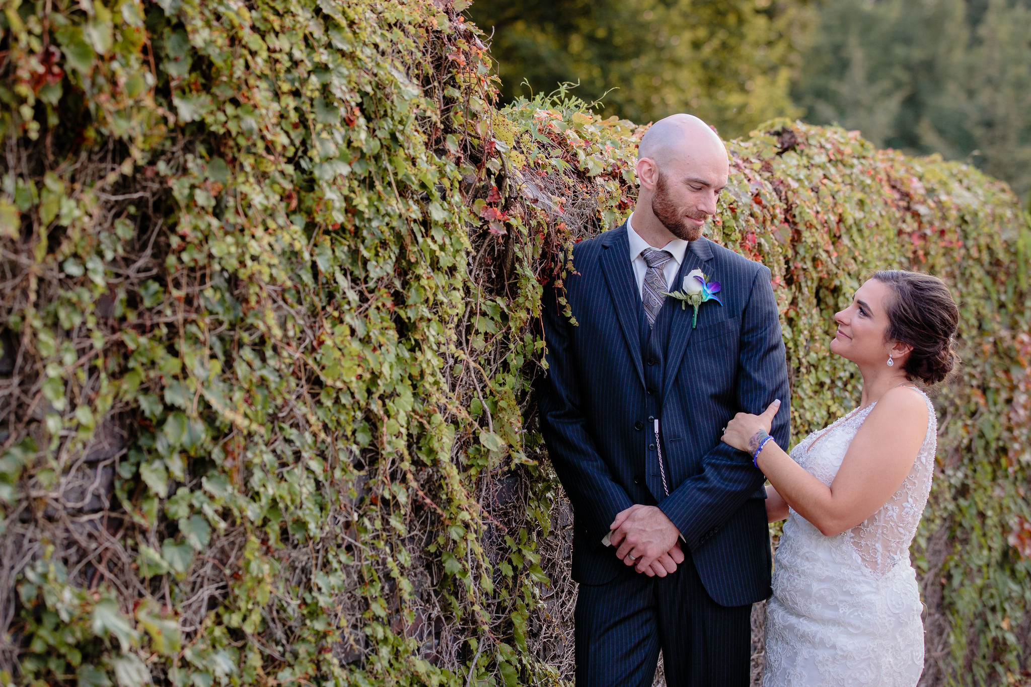 Bride & groom lean against a wall of ivy at the National Aviary