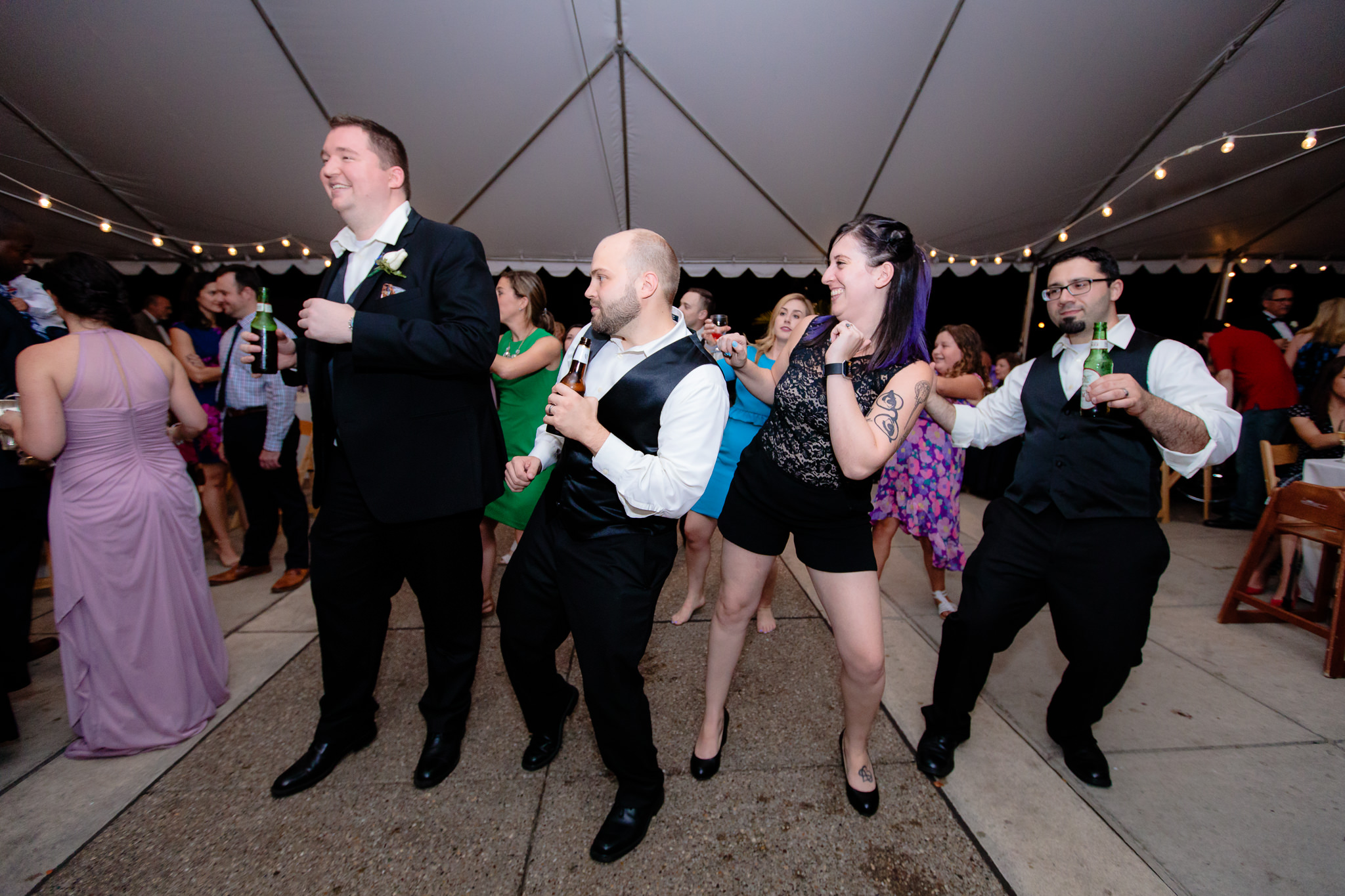 Guests dance at a tented wedding reception at the National Aviary