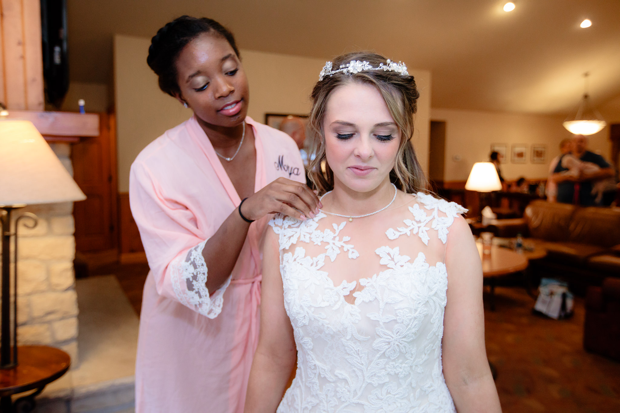Bridesmaids puts a necklace on the bride before her Oglebay wedding