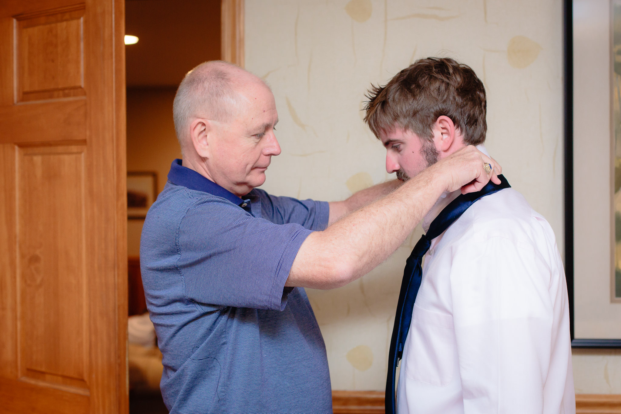 Father of the groom helps him put on his tie at Chambers cottage at Oglebay
