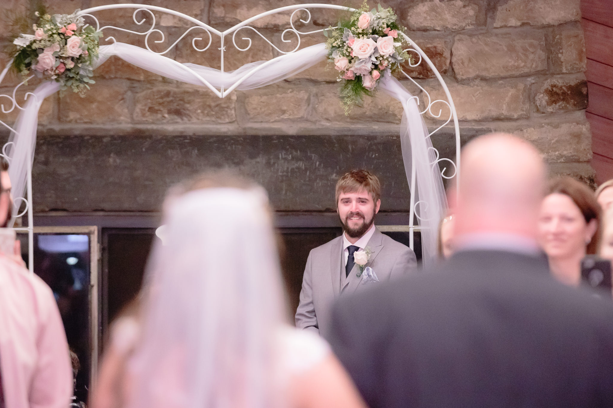 Groom smiles and holds back tears as his bride walks down the aisle at Oglebay