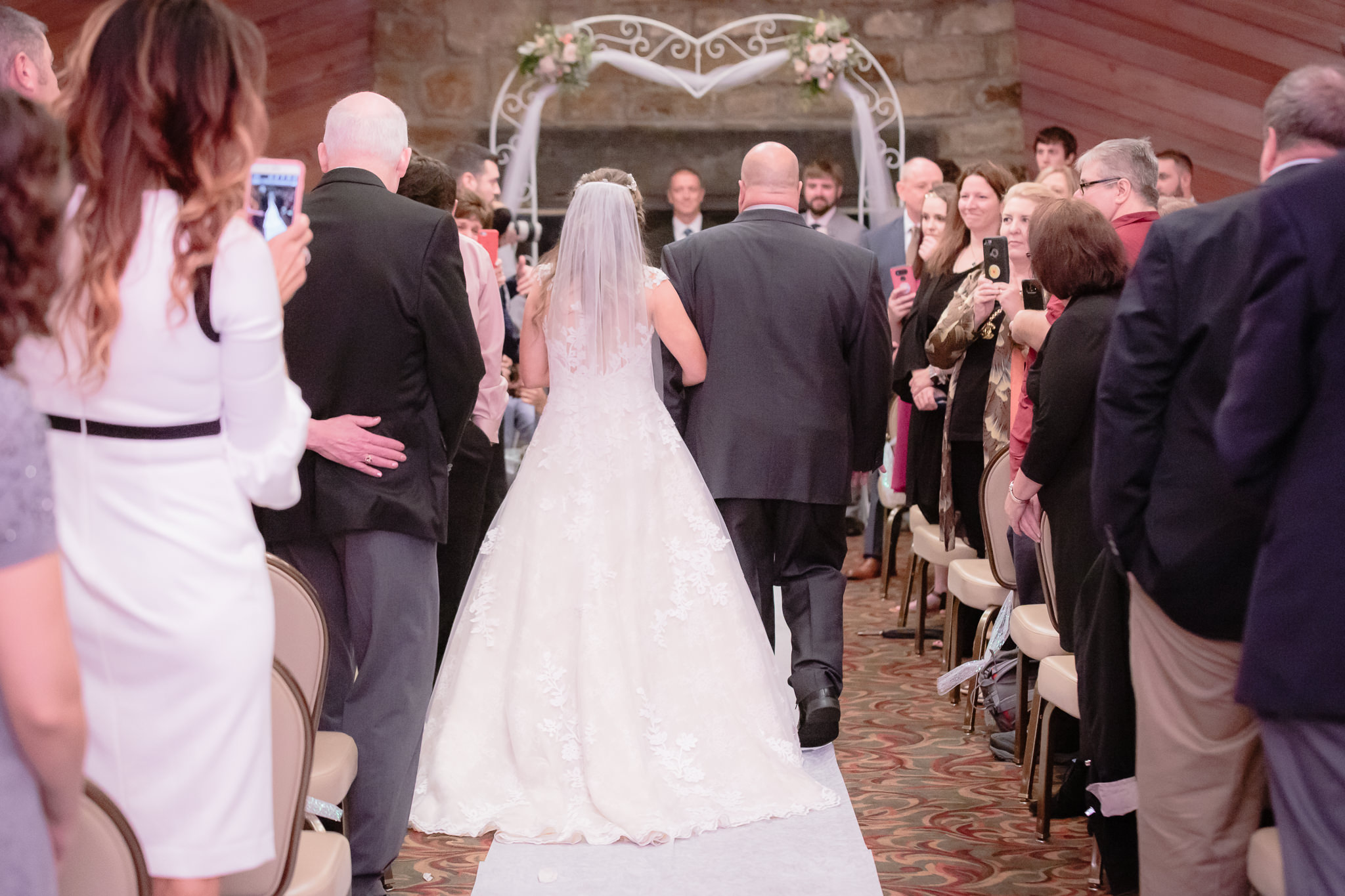 View of the bride walking down the aisle with her father from behind at Oglebay