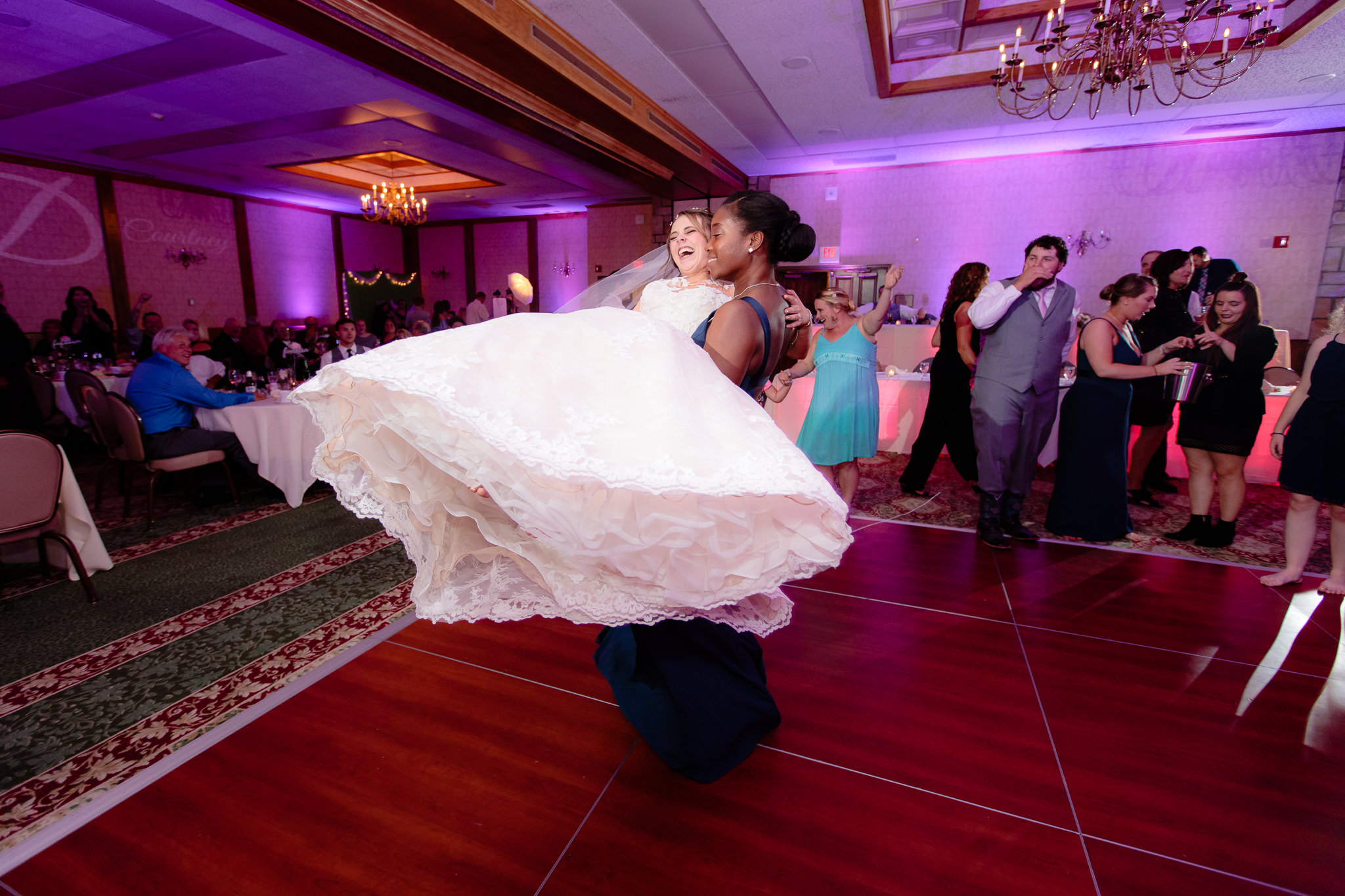 Bridesmaid swings the bride around on the dance floor at Oglebay