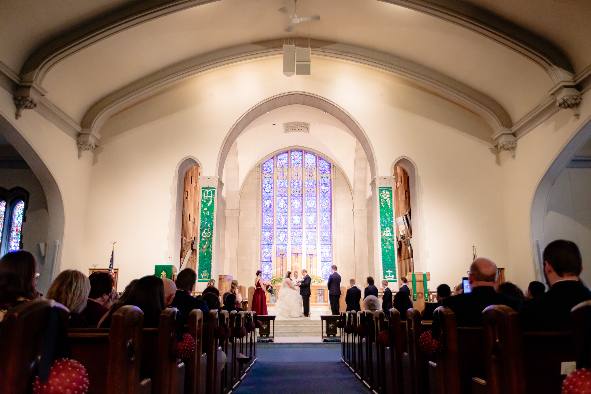 Stained glass windows behind the bride and groom at Mt. Lebanon United Methodist Church