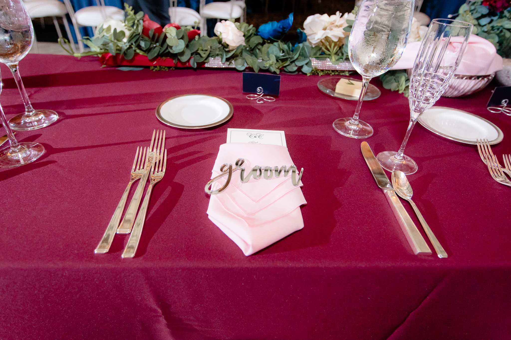 The groom's placesetting with gold silverware atop a maroon table cloth at the Pennsylvanian