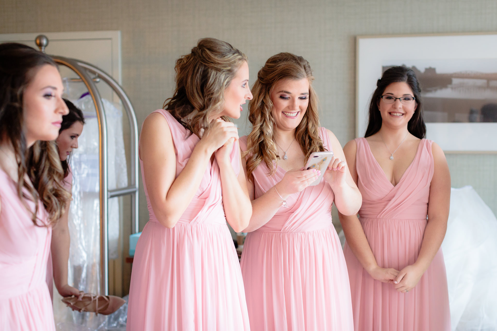 Bridesmaids smile after taking a photo of the bride on their iPhone