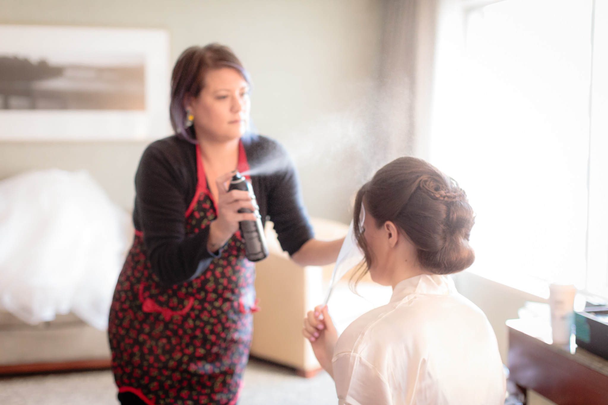 Hair stylist from Salon Nolas sprays the bride's updo