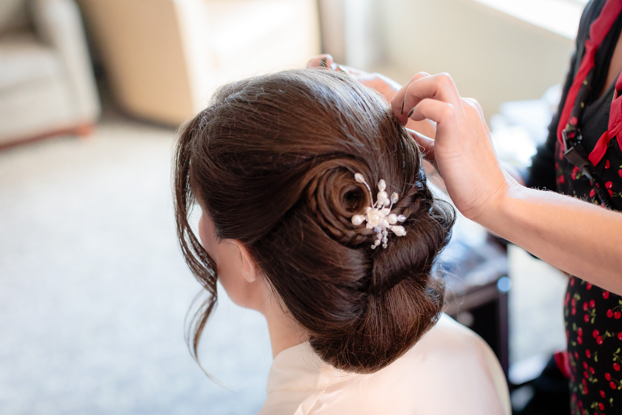 Hair stylist from Salon Nolas puts the finishing touch ups on the bride's updo