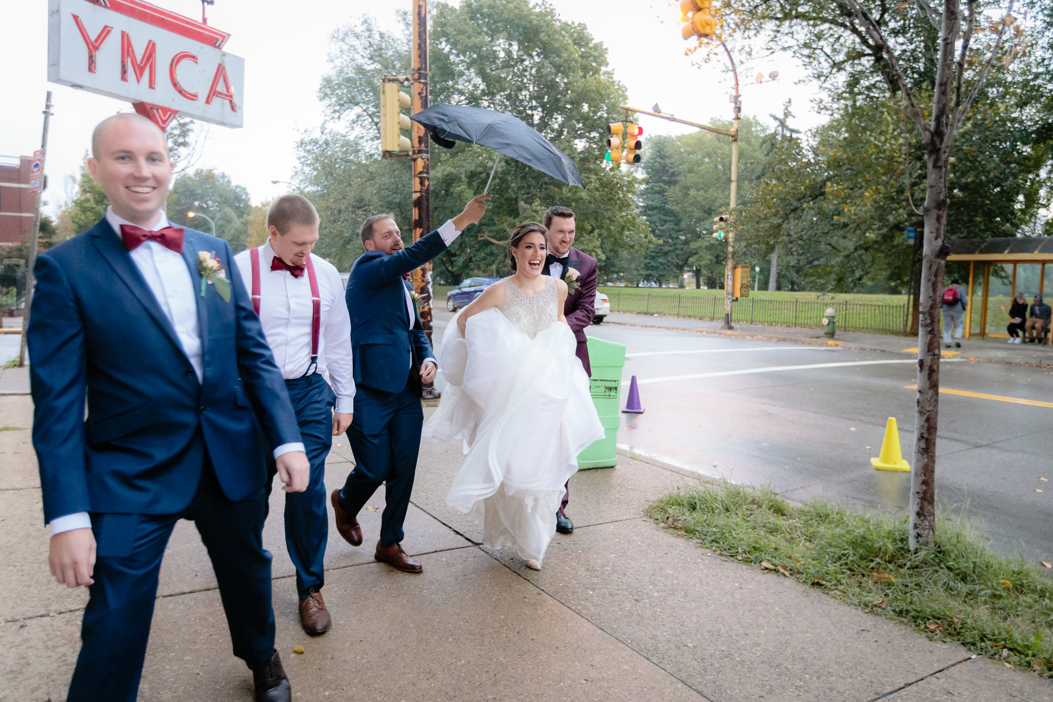 Groomsmen help the bride run for cover during a rainstorm on the North Side of Pittsburgh
