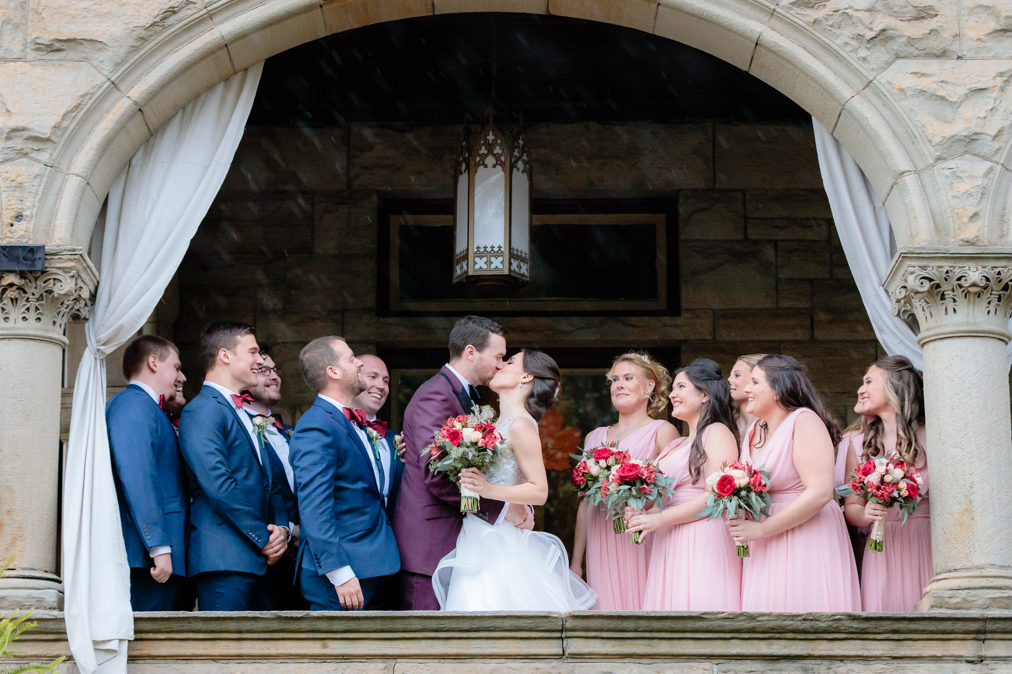 Bride & groom kiss while their bridal party watches on the porch of a North Side house