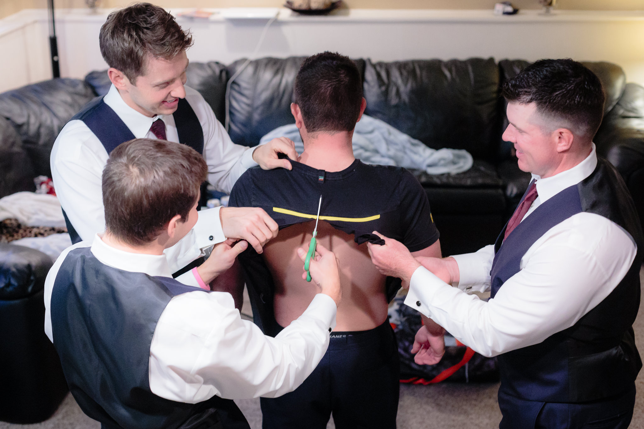 Groomsmen cut the groom's t-shirt off so he doesn't ruin his hair before his Riverside Landing wedding