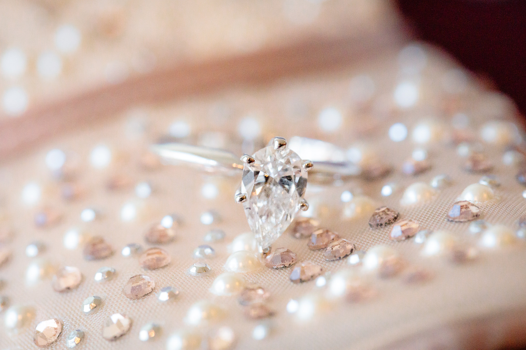 Solitary teardrop diamond engagement ring rests on bride's wedding shoes before her Riverside Landing wedding