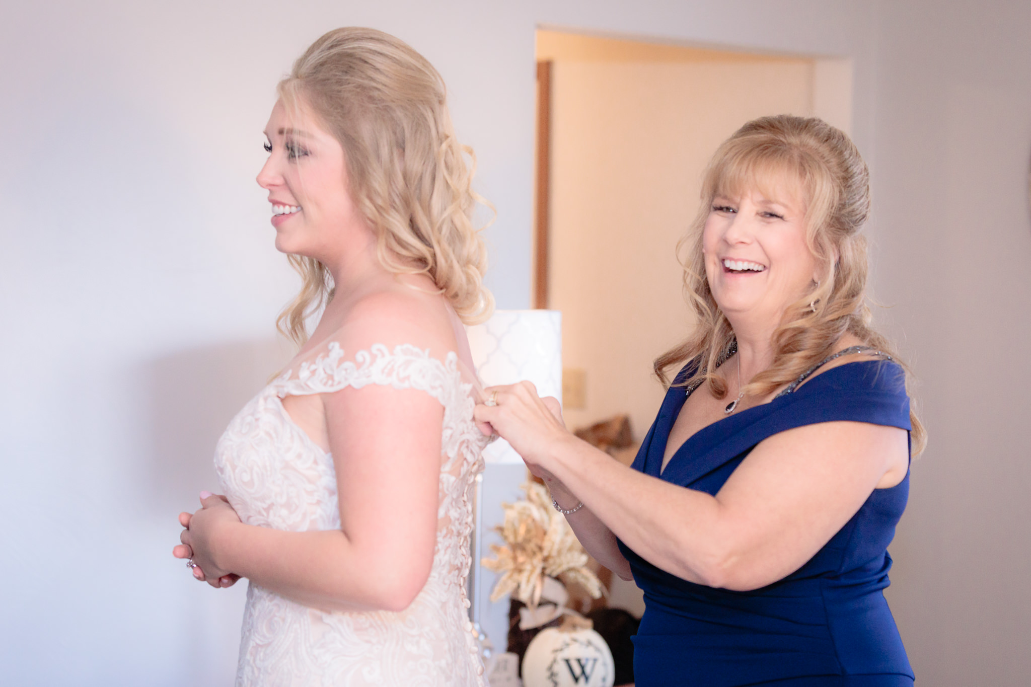 Mother of the bride laughs as she buttons her Allure wedding dress from MB Bride