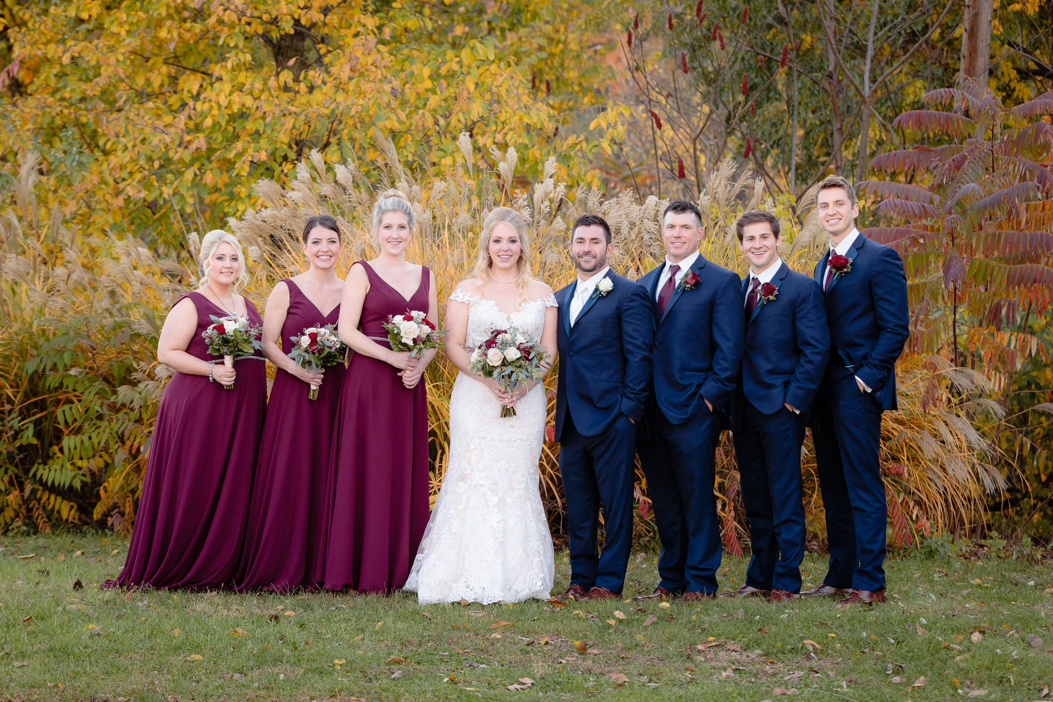 Bridal party in burgundy Morilee dresses and navy tuxes before a Riverside Landing wedding reception